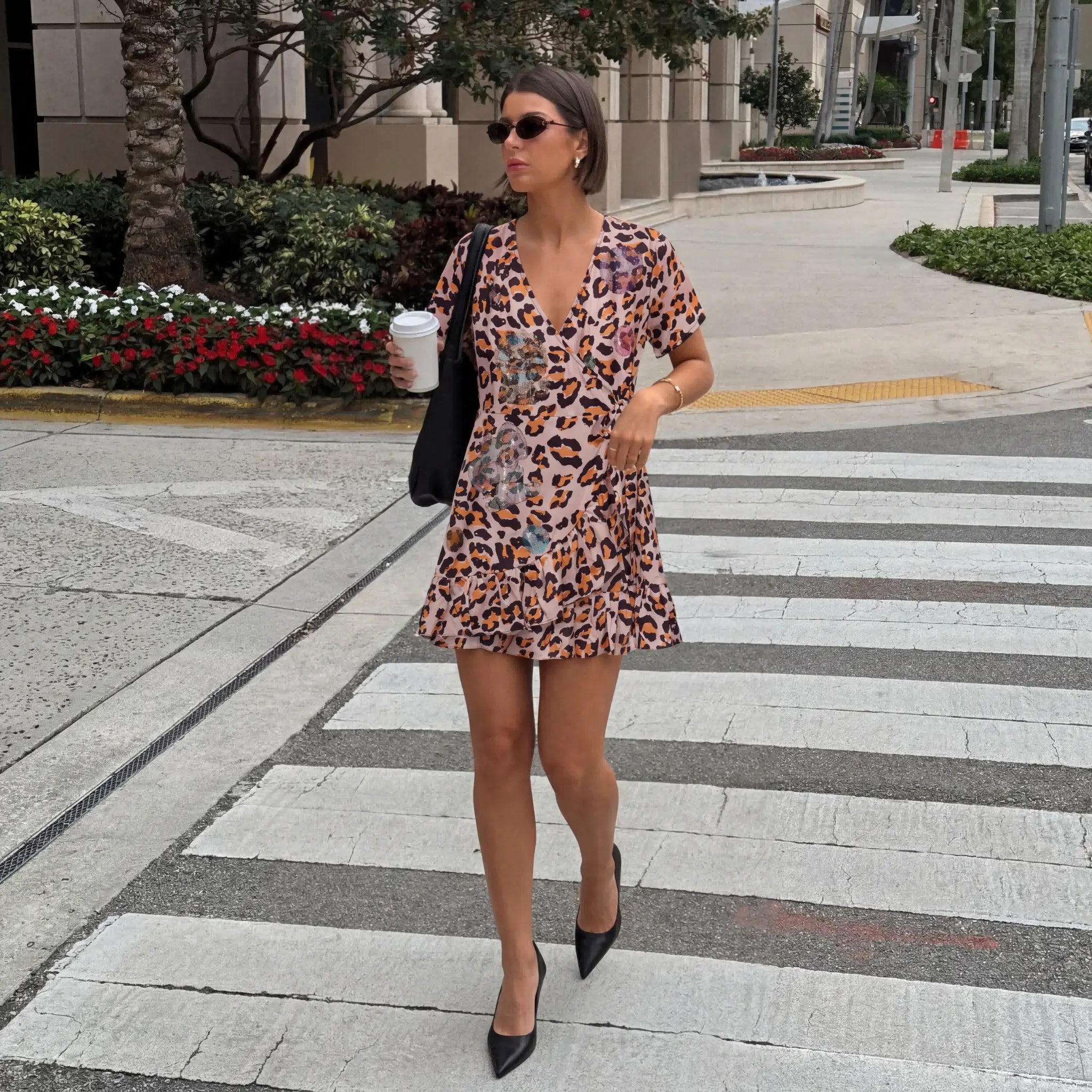 Woman in a leopard print dress crossing a street with a coffee cup. TCH Leopard Rhinestone Animal Embellished Dress