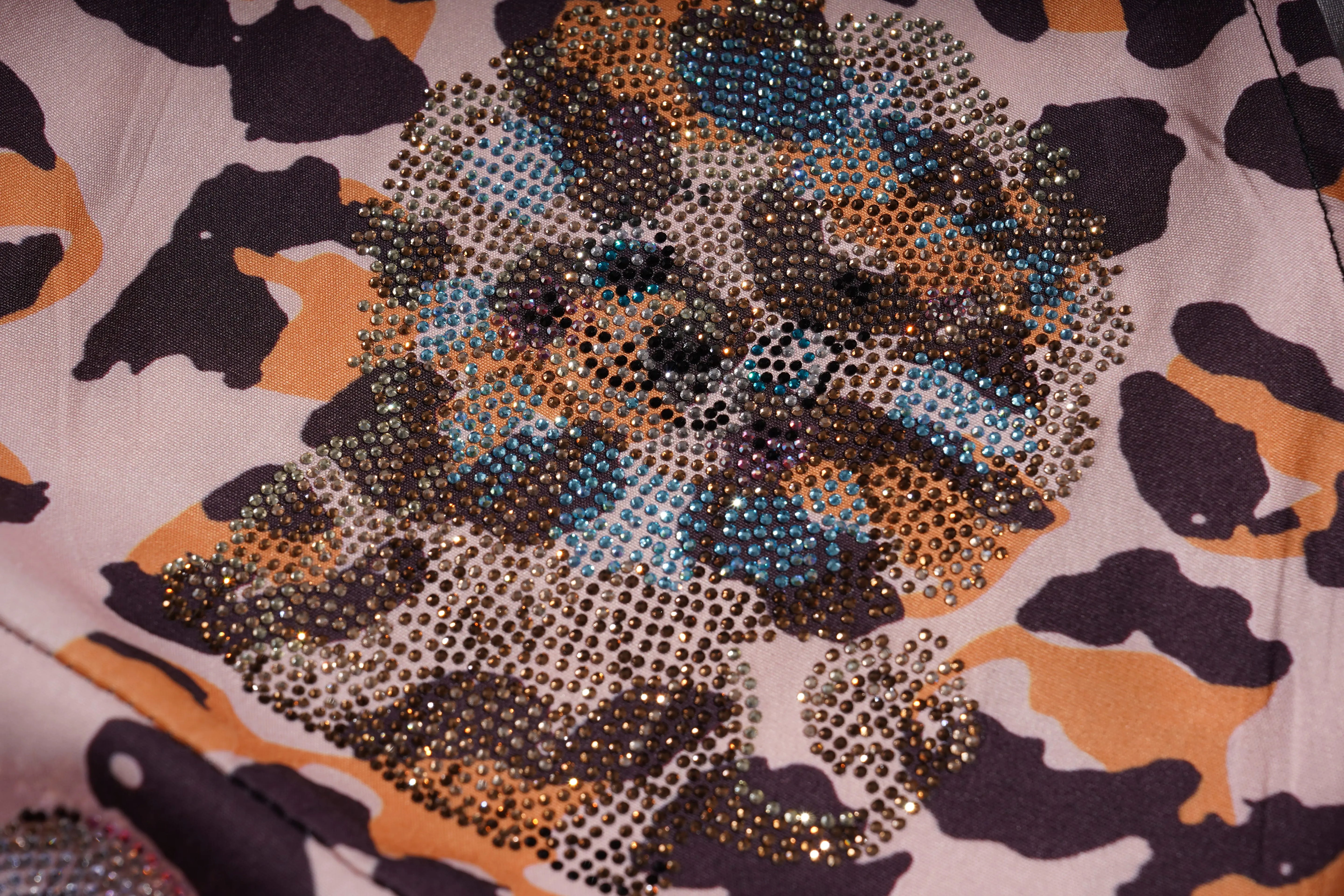 Close-up of a patterned fabric with rhinestone embellishments on a camouflage background. TCH Leopard Rhinestone Animal Embellished Dress