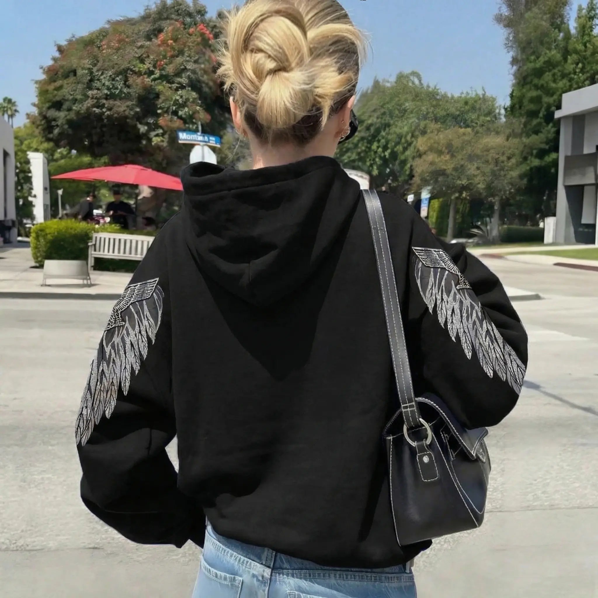 Person wearing a black hoodie with wings on the back, standing outdoors. TCH Luck Dog Rhinestone Hooded Sweatshirt-