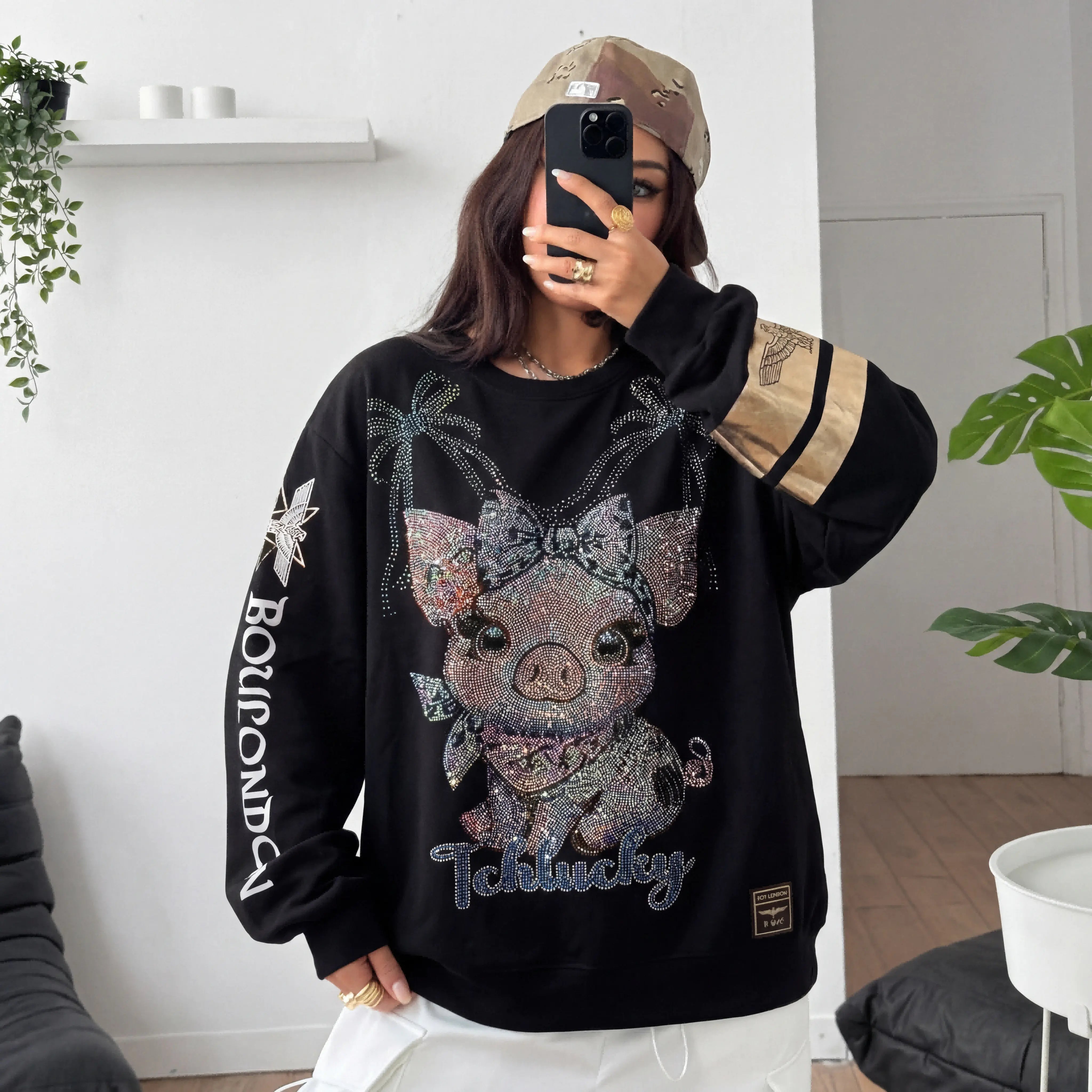 Person wearing a black sweatshirt with a decorative pig design indoors. TCH Lucky Pig Rhinestone Sweatshirt