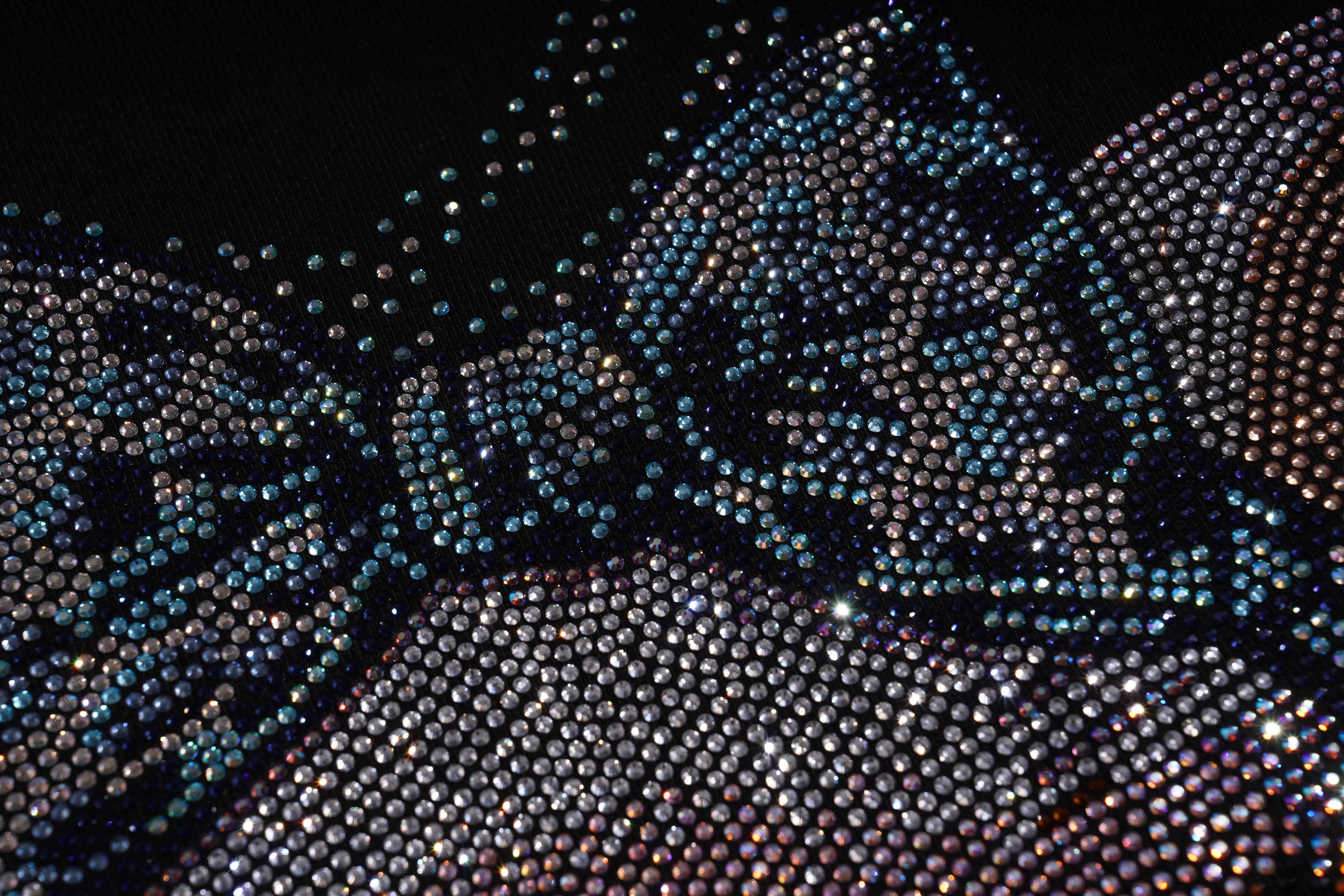 Close-up of a textured fabric with a pattern of small beads or stones. TCH Lucky Pig Rhinestone Sweatshirt
