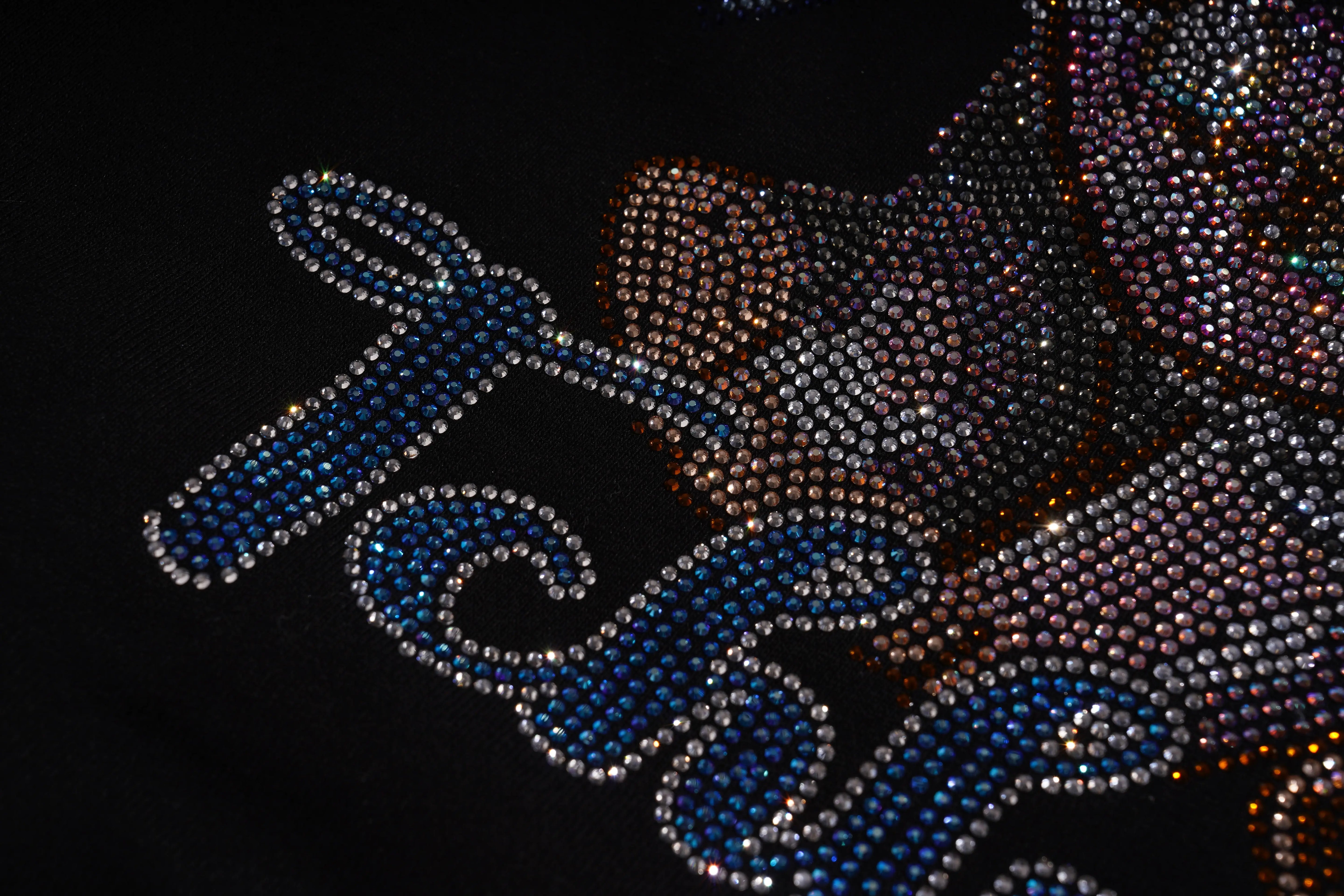 Close-up of a rhinestone-embellished garment with 'Tres' text on a dark background, TCH Lucky Pig Rhinestone Sweatshirt