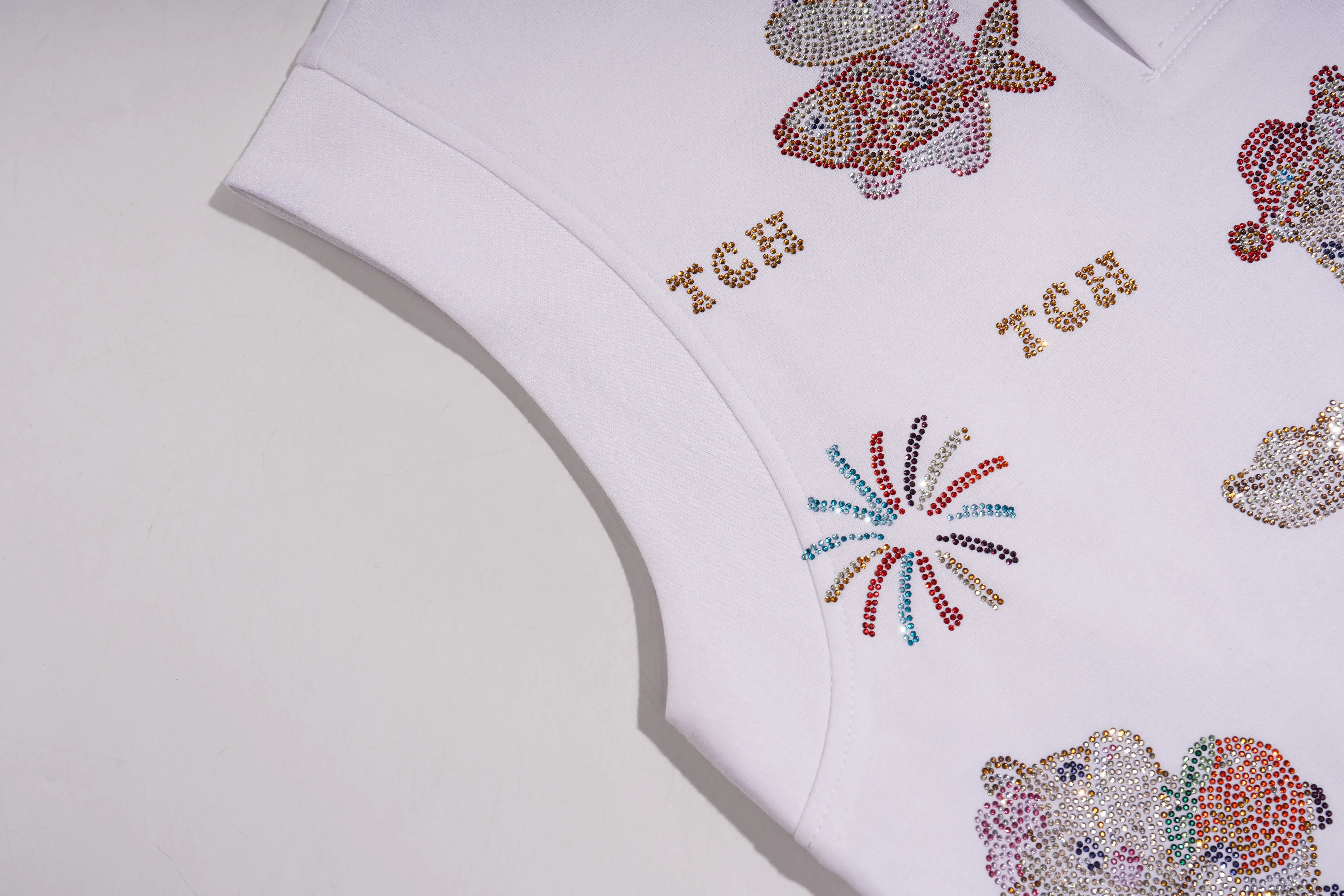 White garment with colorful embellishments and 'TCH' branding on a light gray background, TCH Lucky Pony Rhinestone Sleeveless Polo Shirt