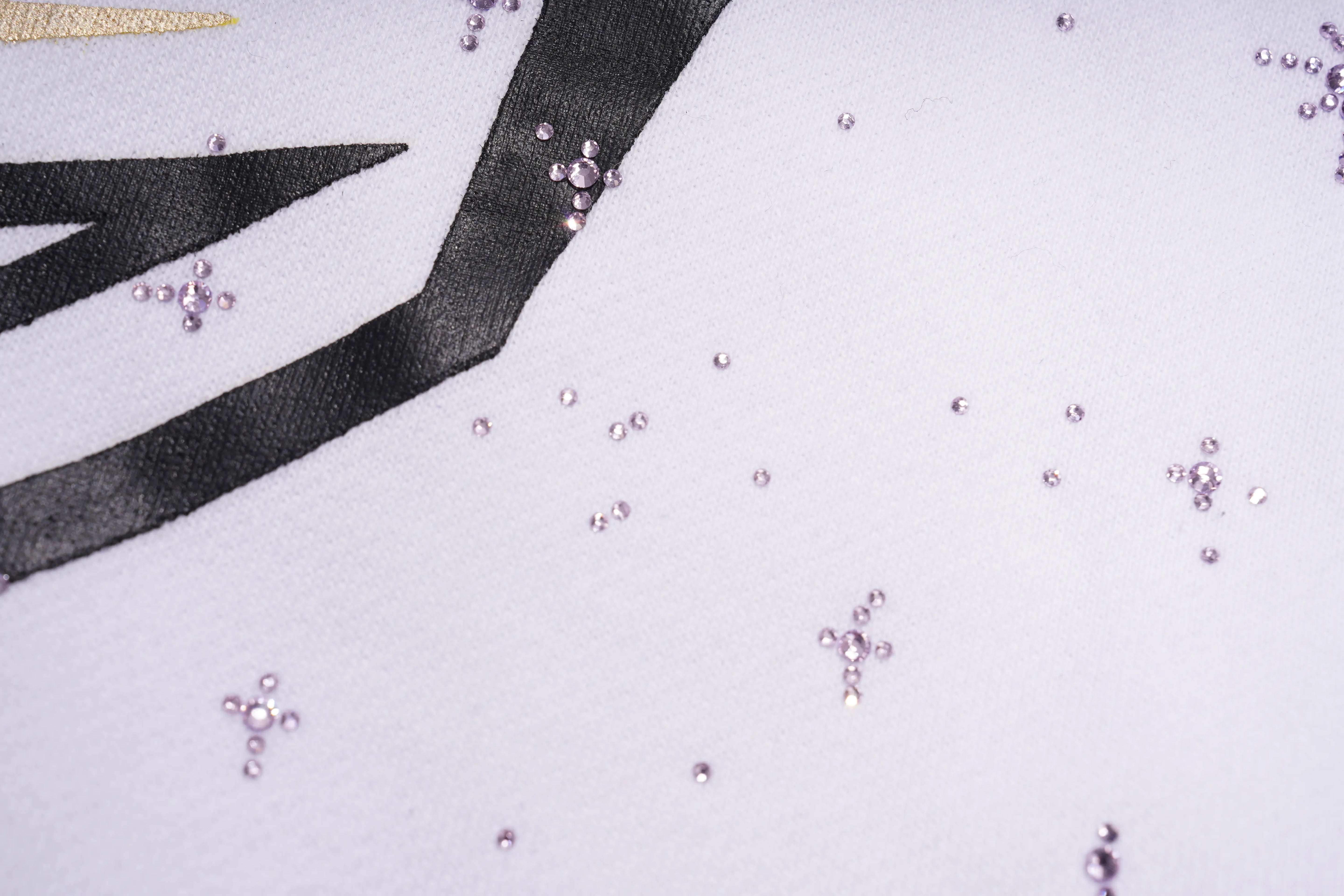 Close-up of a white surface with black geometric design and small pink embellishments. TCH Mech Graphic Rhinestone Crew Neck Sweatshirt