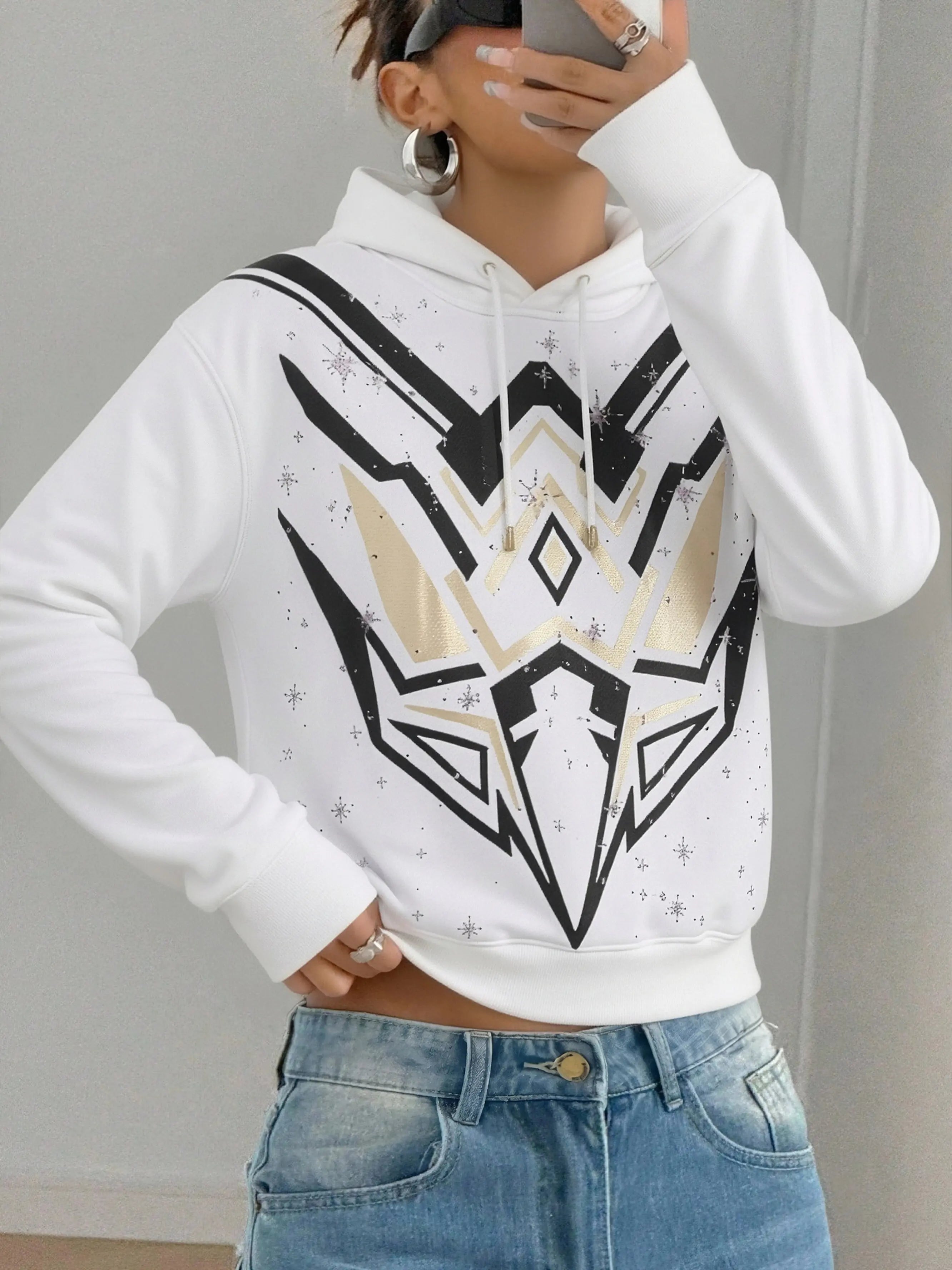 Person wearing a white hoodie with a black and gold geometric design, standing against a plain background. TCH Mech Graphic Rhinestone Crew Neck Sweatshirt