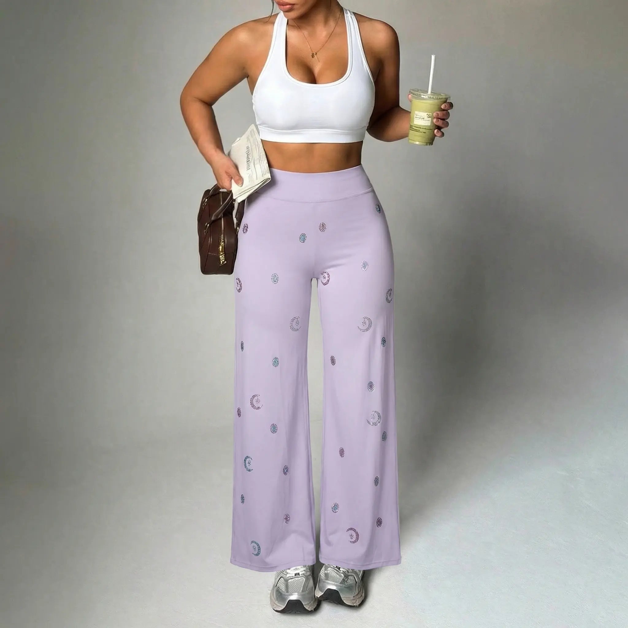 Woman wearing a white sports bra and lavender pants with a pattern, holding a drink and a book. TCH Moonlight Rhinestone Wide-Leg Pants