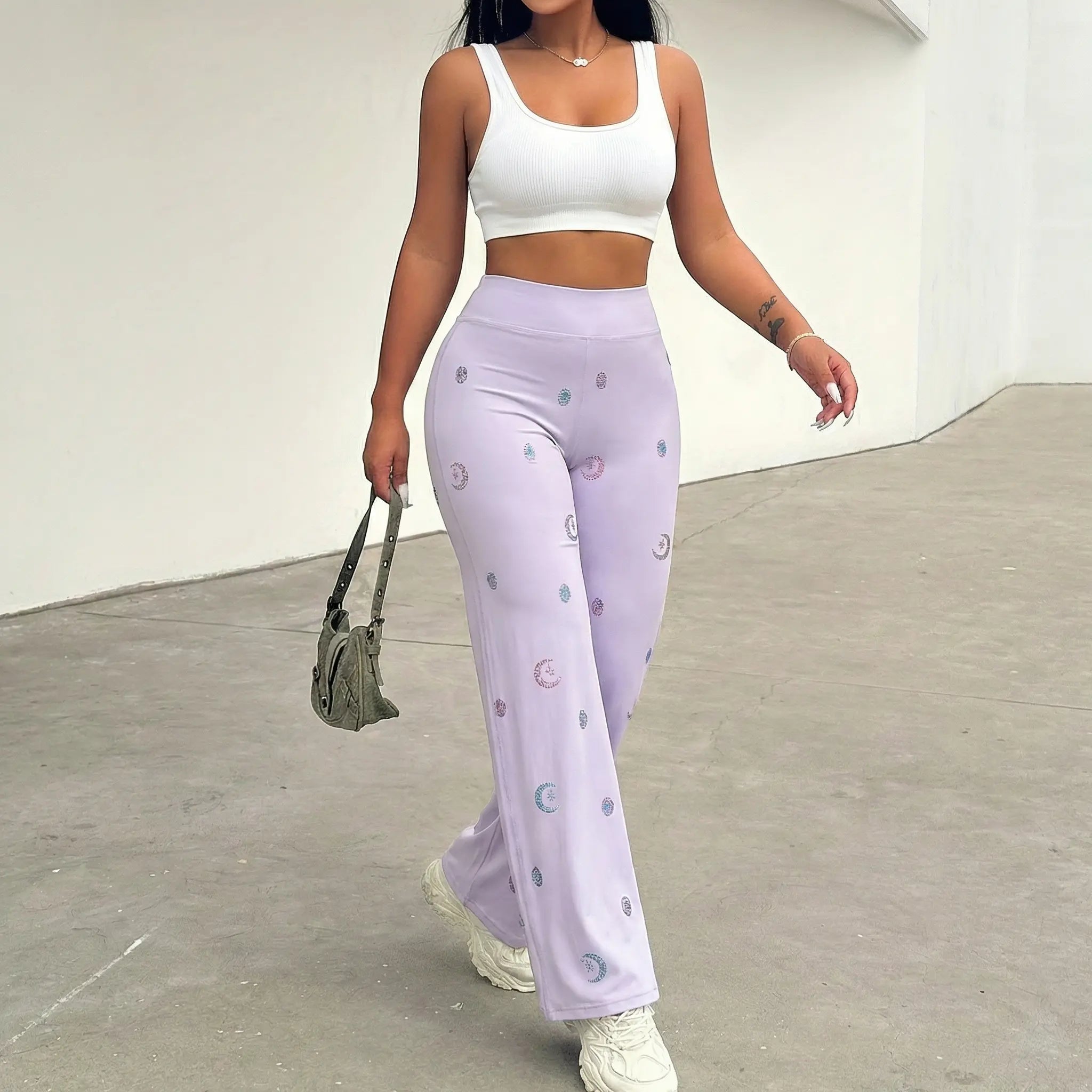 Woman wearing a white crop top and light purple pants with a pattern, holding a green bag indoors. TCH Moonlight Rhinestone Wide-Leg Pants