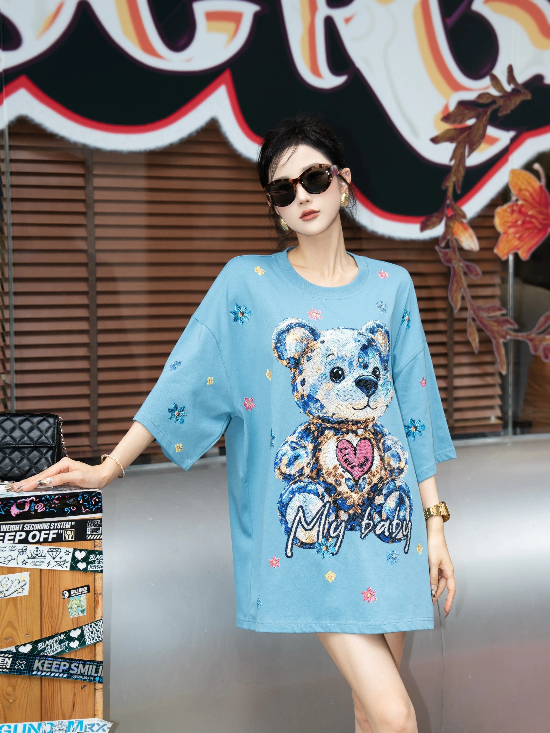 Woman wearing a blue dress with a teddy bear design in an indoor setting. TCH My Baby Rhinestone Bear Oversized Blue T-Shirt
