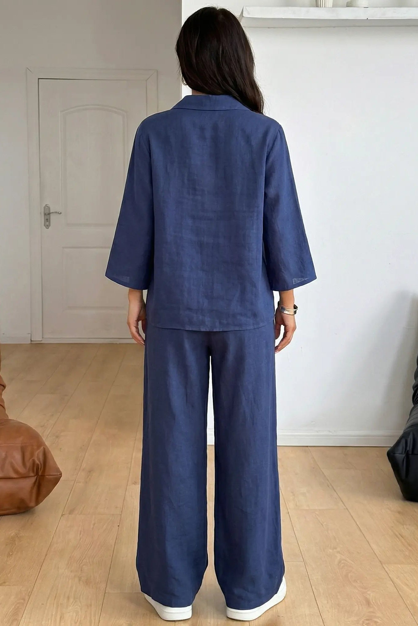 Person wearing a blue outfit standing in a minimalistic room with a brown leather chair and black cushion. TCH Navy Rhinestone Dog Matching Set