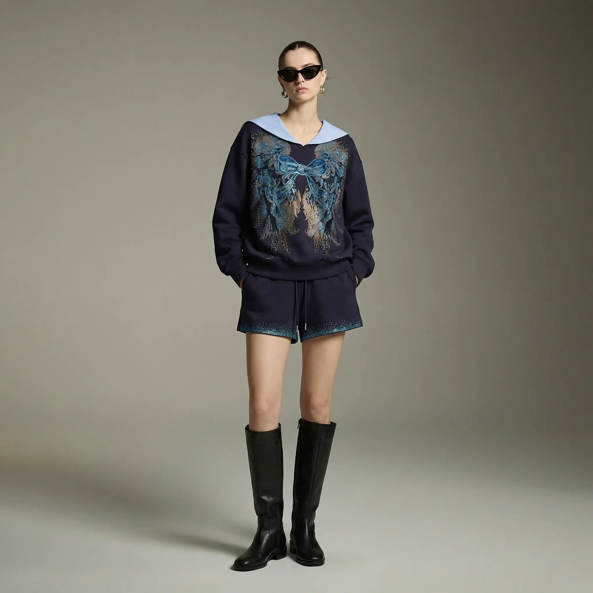 Model wearing a dark sweater with abstract design, shorts, and black boots on a neutral background, TCH Navy Sailor Bow Wings Rhinestone Two-Piece Set