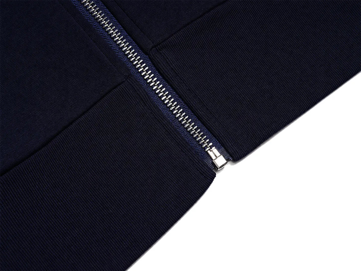 Close-up detail of a dark navy ribbed fabric garment with a silver metal zipper running diagonally across the frame, set against a clean white background. TCH Navy Teddy Bear Rhinestone Zip Hoodie