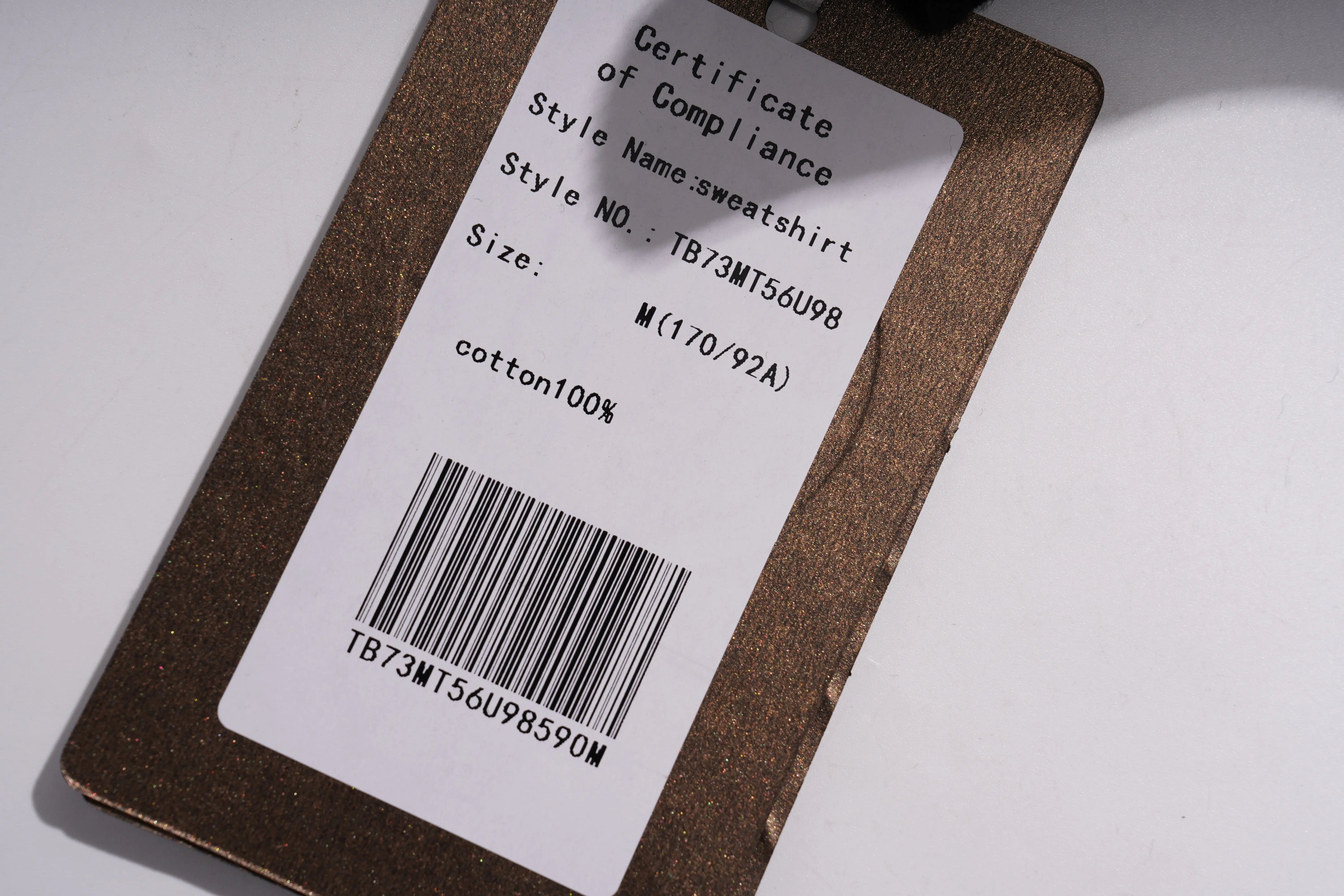 Product tag with certificate of compliance details on a white background， TCH Peacock Embroidered Rhinestone Sweatshirt