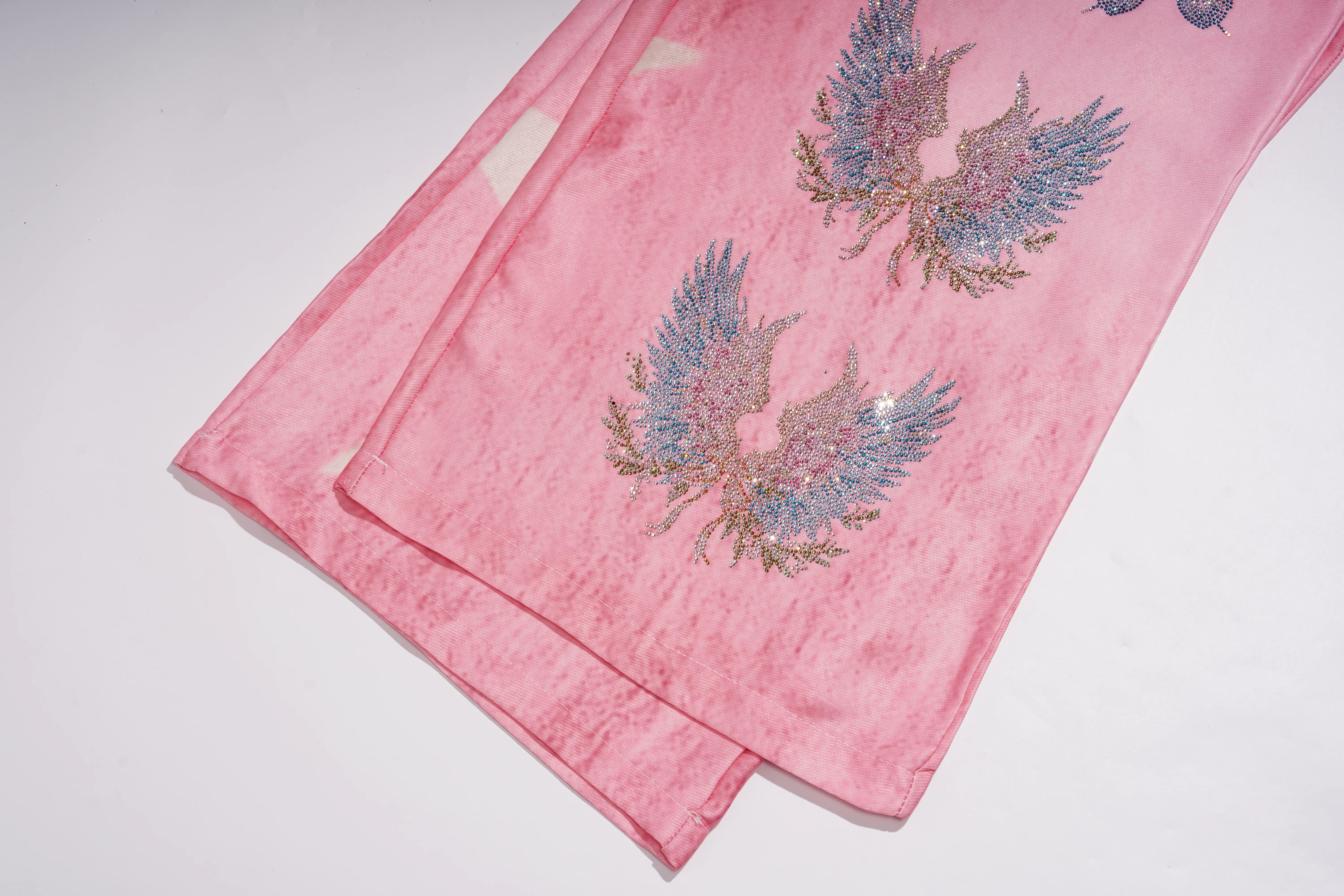 A folded pink fabric garment, likely a kurta or dress, featuring two embroidered phoenix designs in blue, gold, and silver thread on a white background. TCH Pink Butterfly Rhinestone Star Wide Leg Jeans