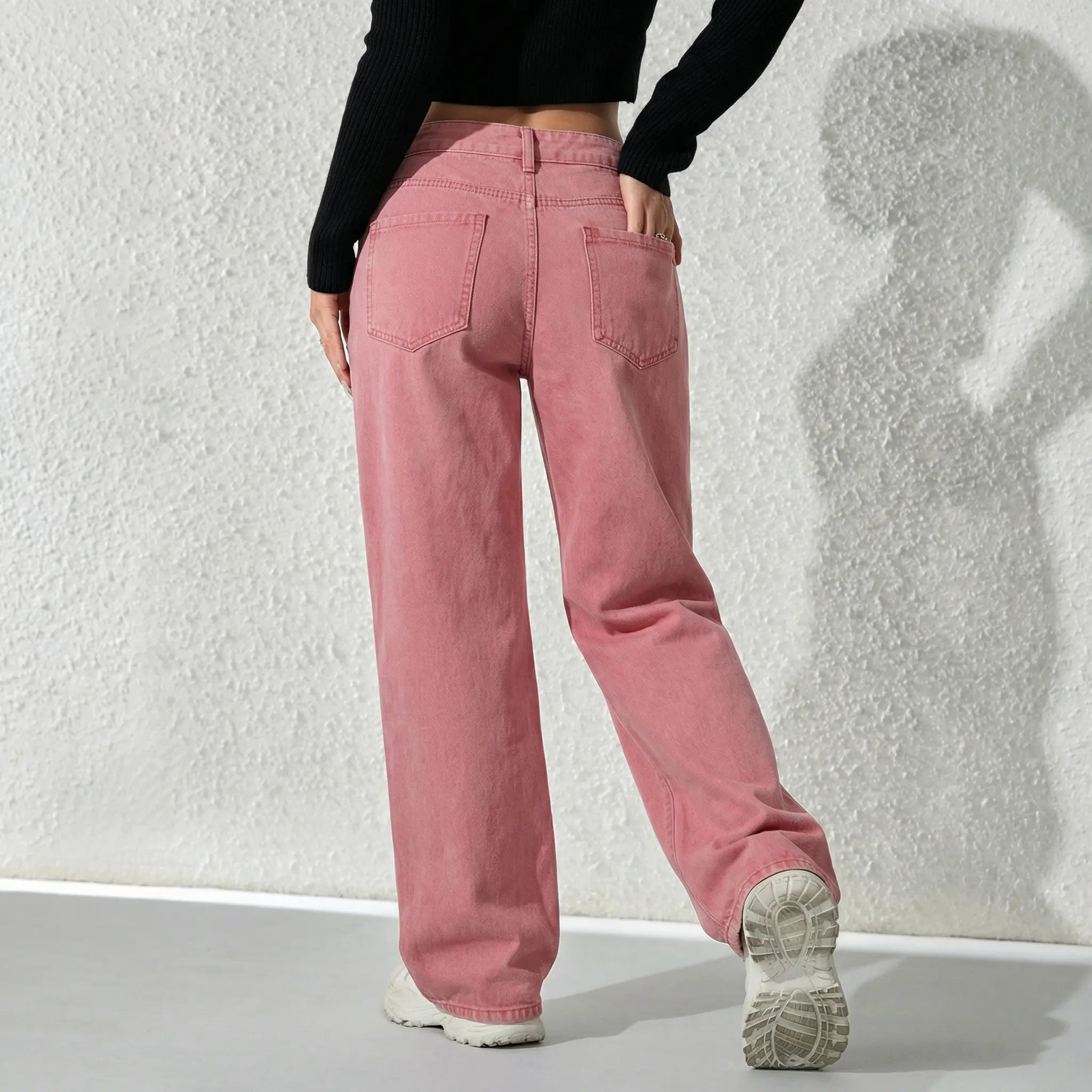 Person wearing pink pants and a black top against a textured white wall. TCH Pink Moonlight Rhinestone Denim Jeans
