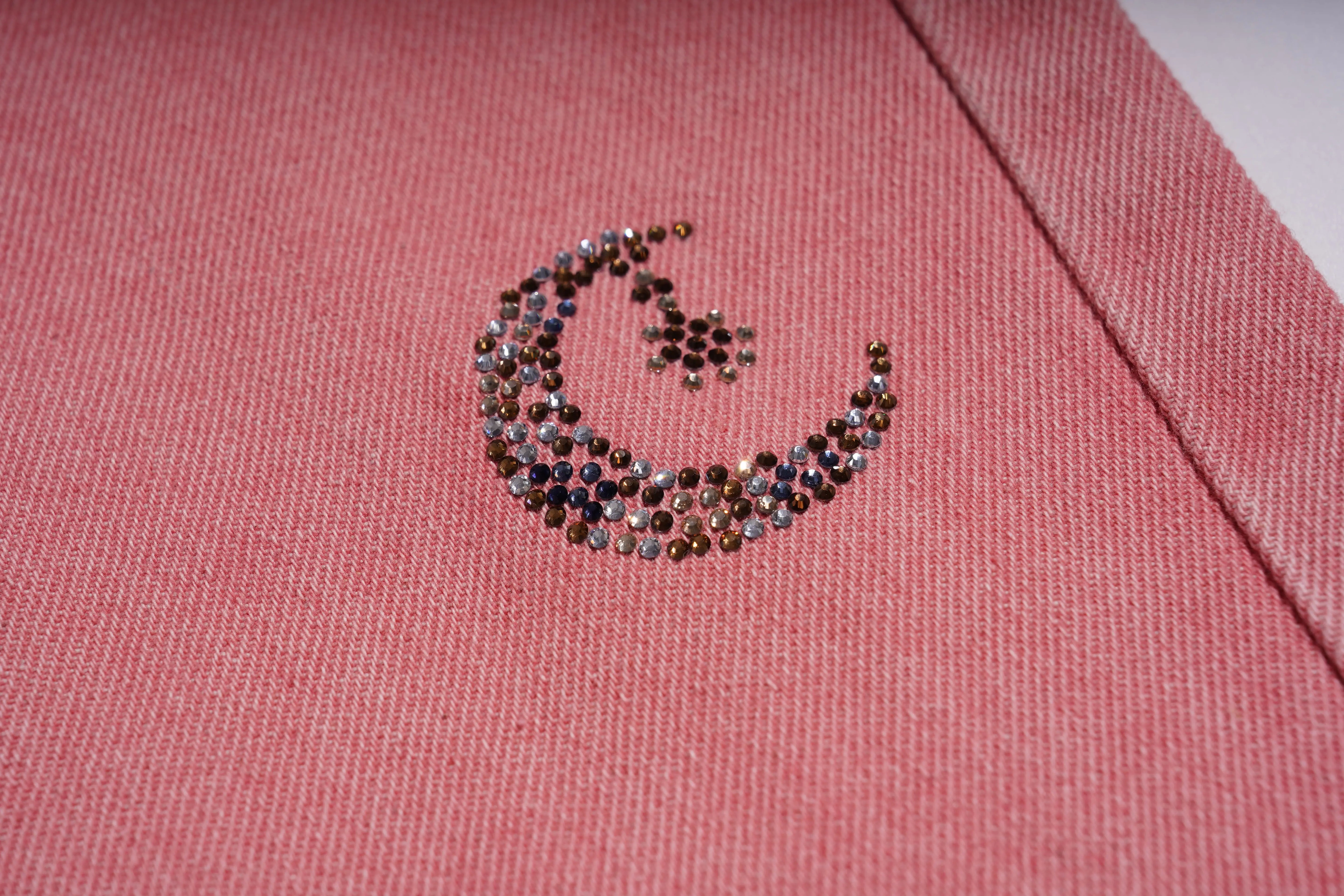 Pink fabric with a decorative crescent moon design made of small stones. TCH Pink Moonlight Rhinestone Denim Jeans