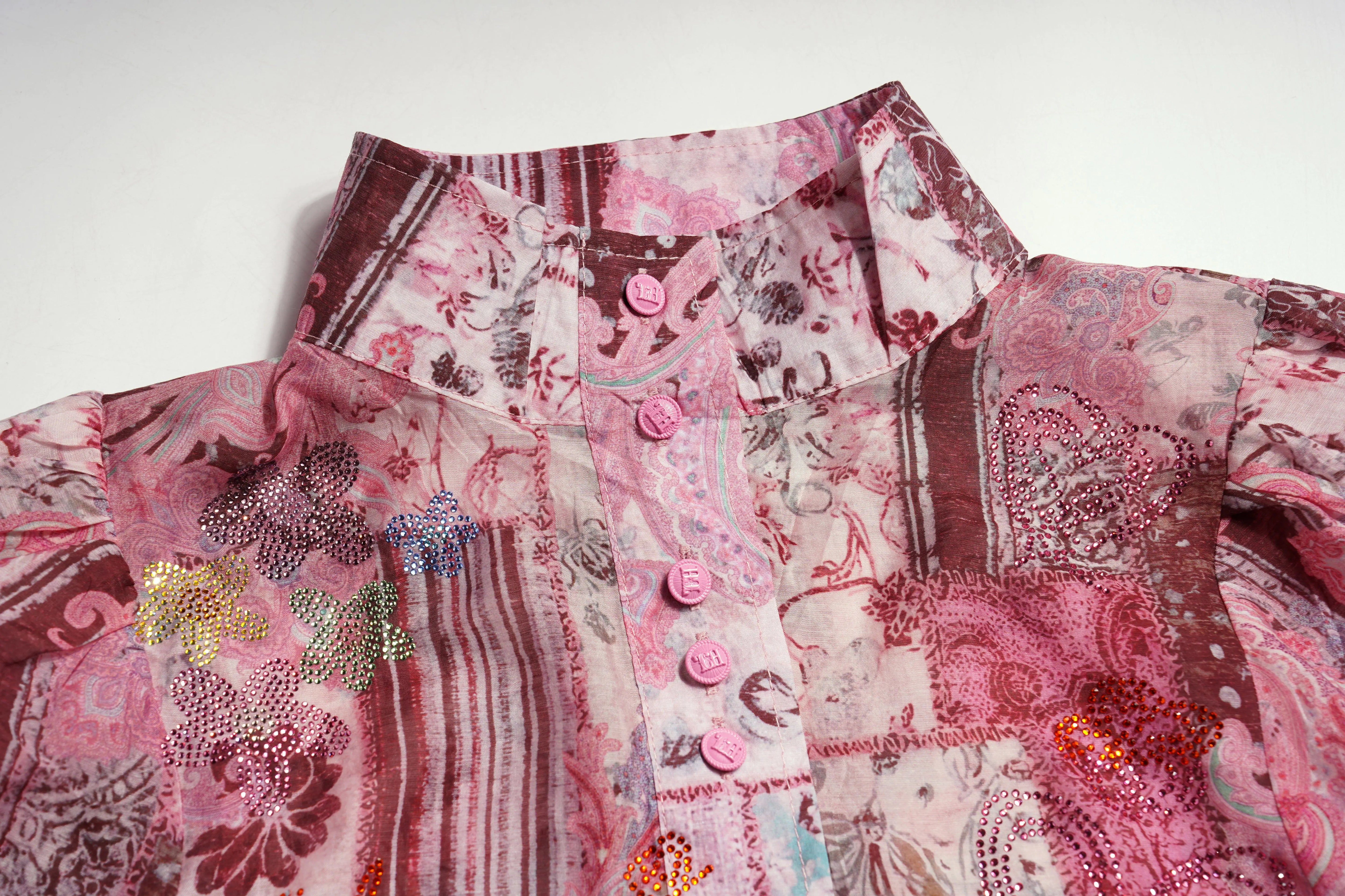 Stack of patterned fabric swatches in pink and red tones. TCH Pink Patchwork Rhinestone Floral Shirt
