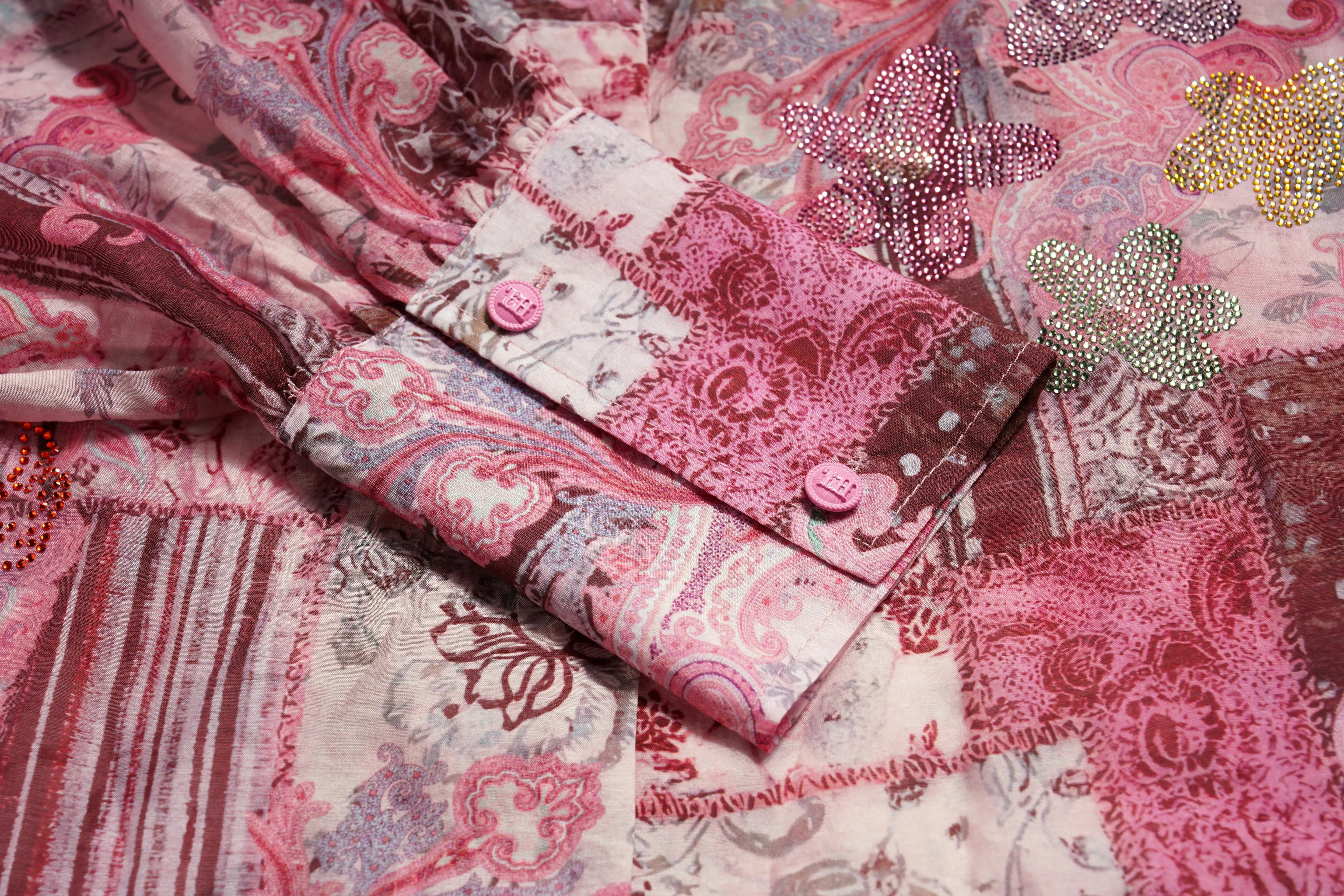 Close-up of a pink and white patterned fabric with embellishments. TCH Pink Patchwork Rhinestone Floral Shirt