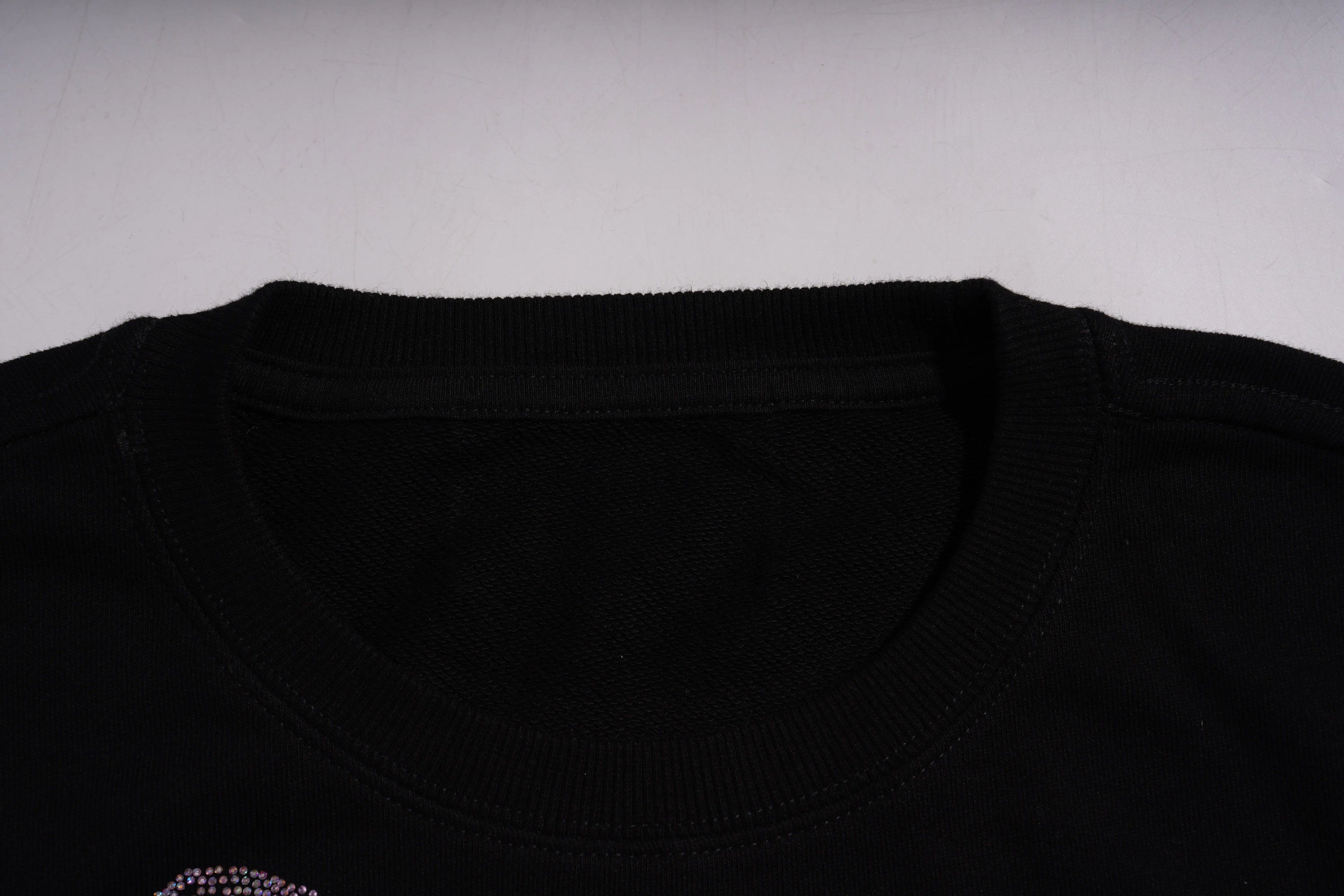 Close-up of a black shirt collar on a gray background, TCH Pink Teddy Rhinestone Sweatshirt
