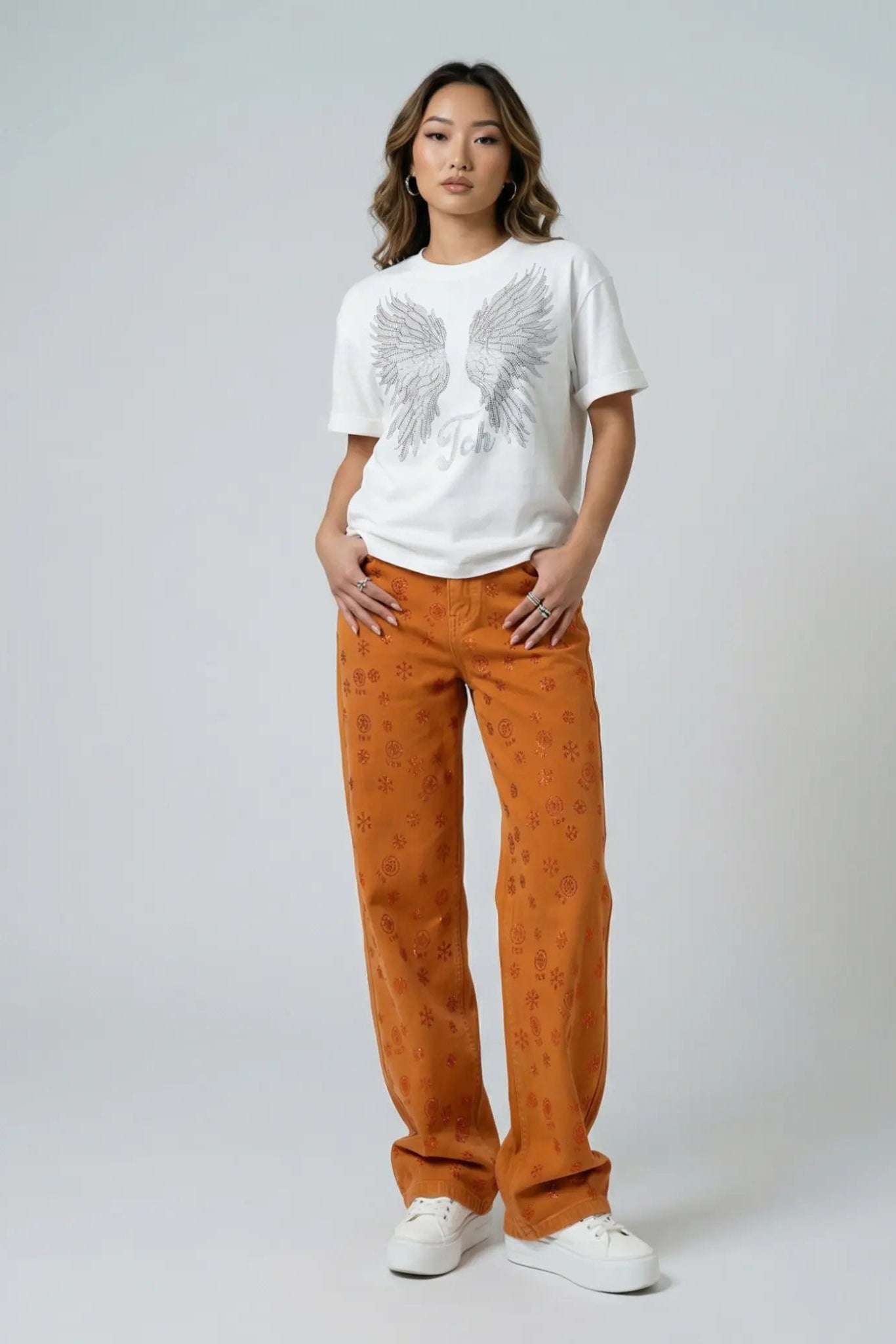 Person wearing a white t-shirt with an eagle design and orange pants on a plain background, TCH Red Snowflake Rhinestone Brown Denim Jeans