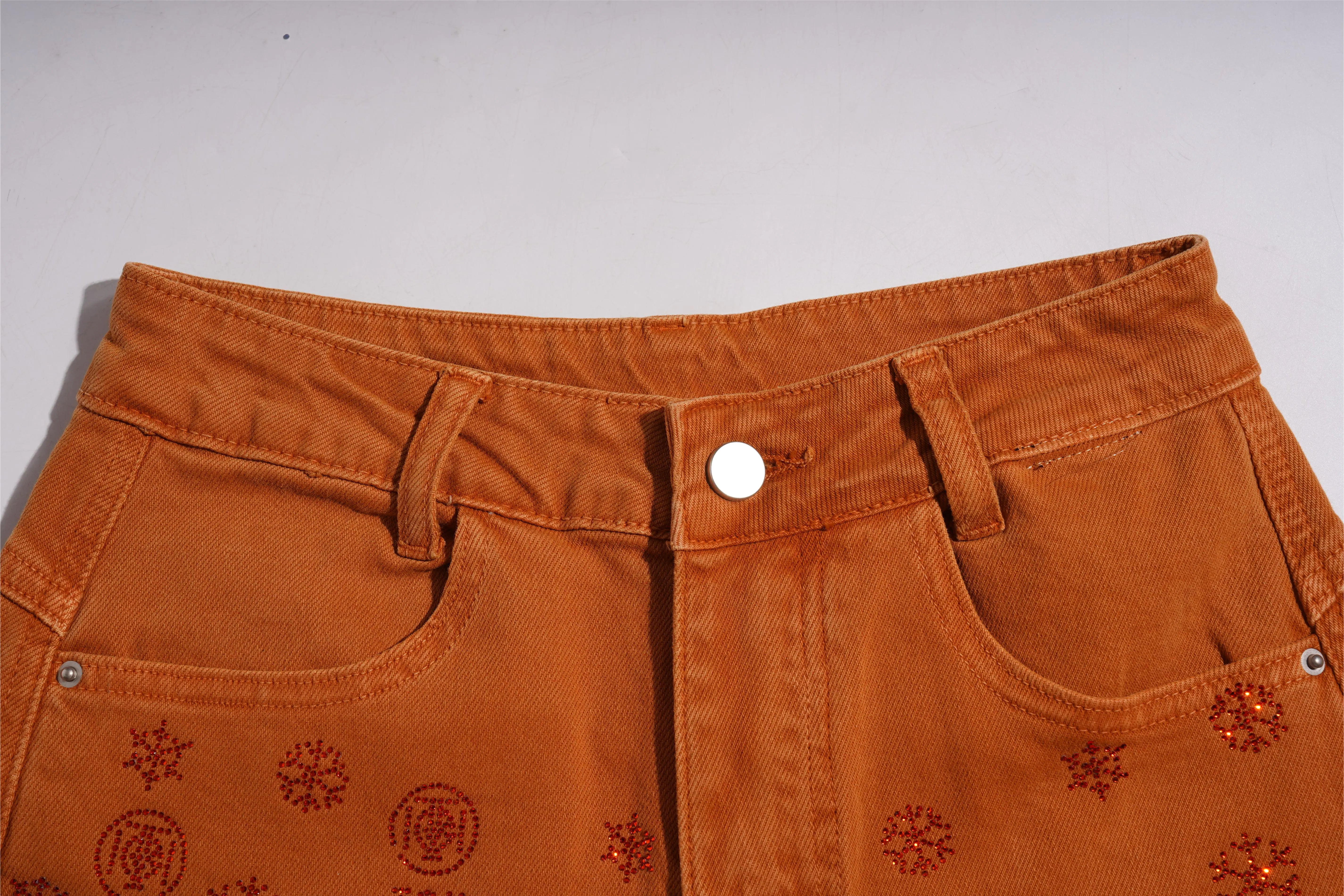 Close-up of orange pants with floral patterns on a white background, TCH Red Snowflake Rhinestone Brown Denim Jeans
