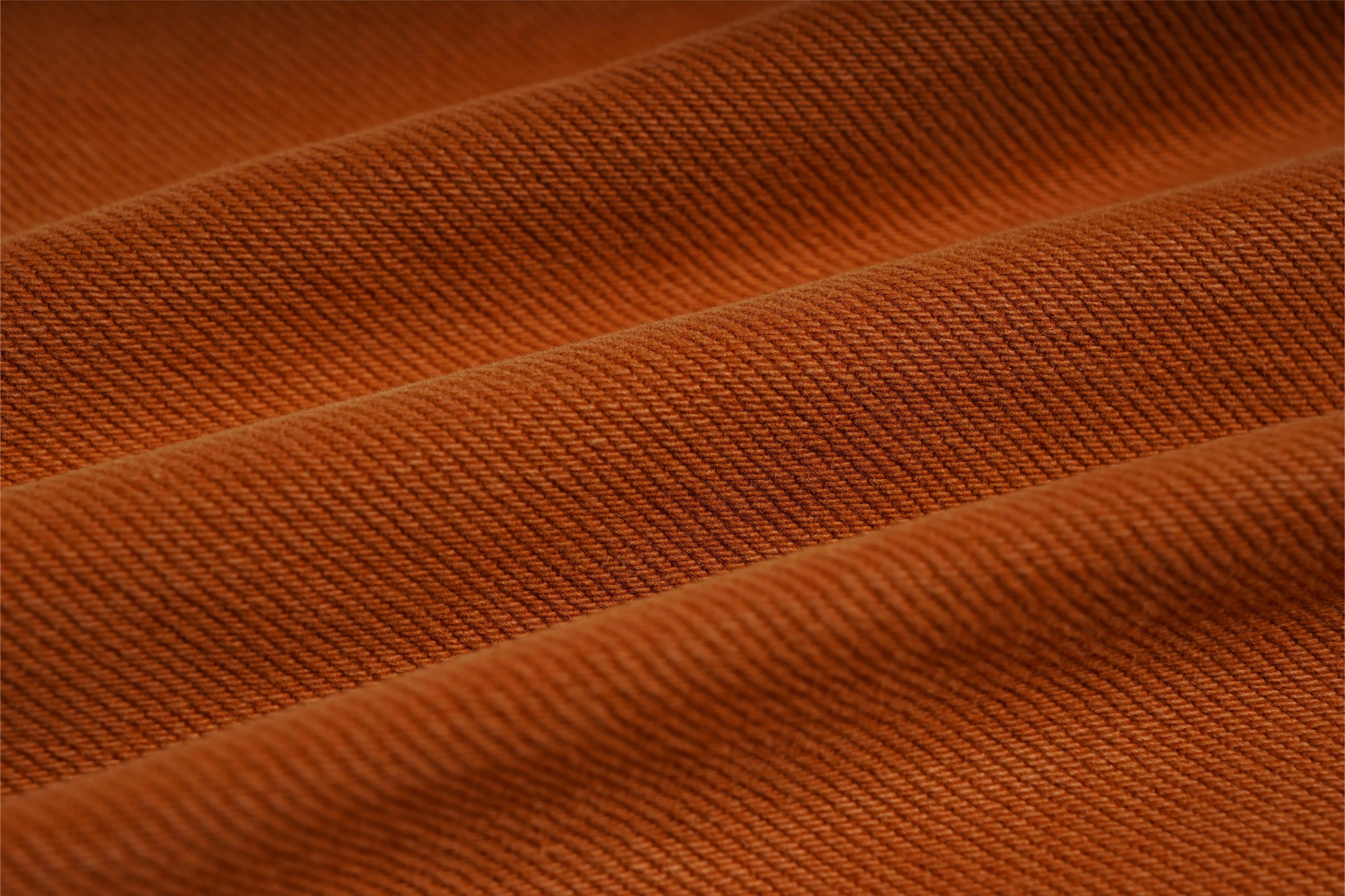 Close-up of orange fabric with visible texture, TCH Red Snowflake Rhinestone Brown Denim Jeans