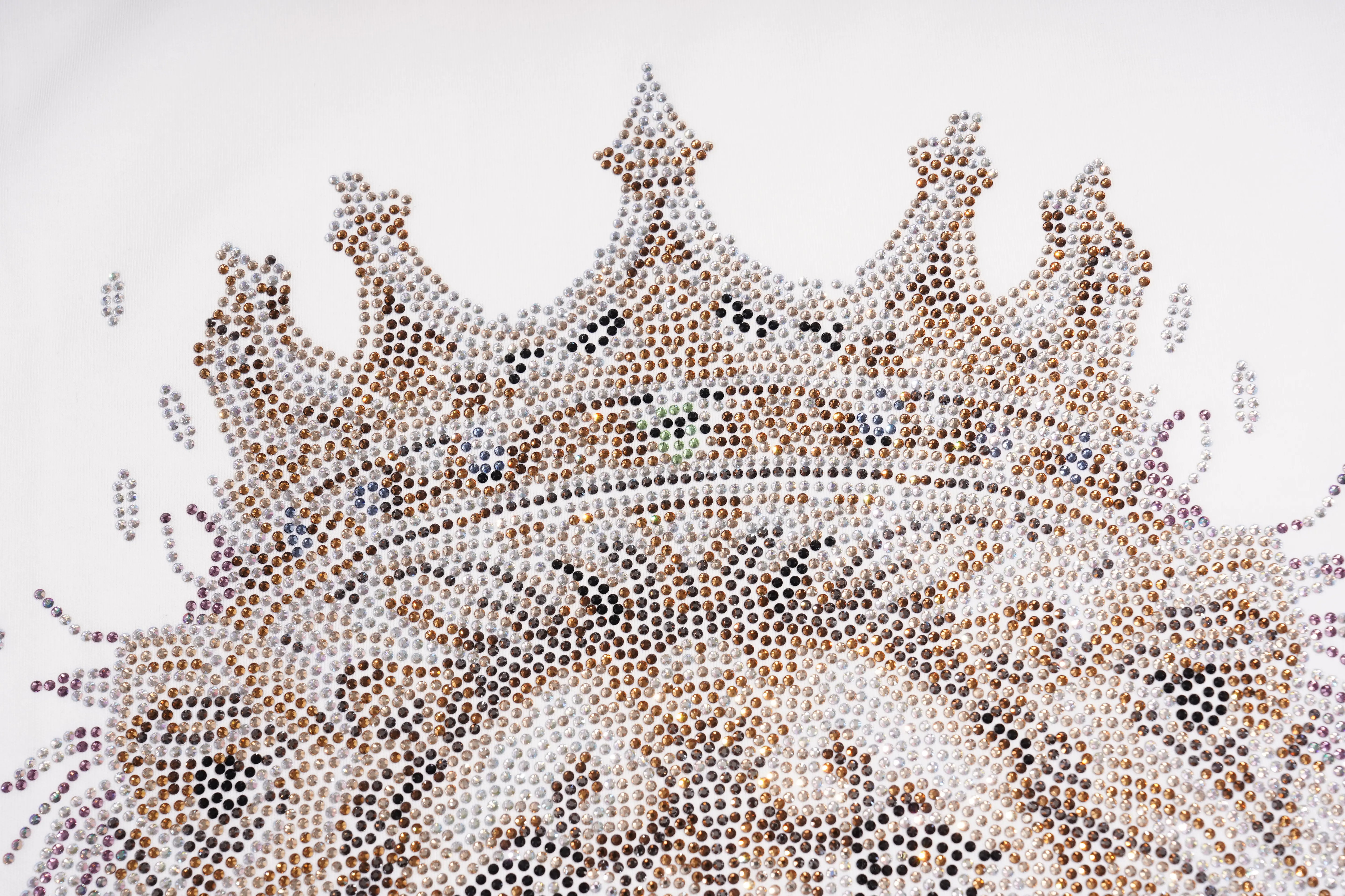 A close-up of a crown-like decorative design made from many small rhinestones and beads, featuring pointed peaks and ornate detailing on a plain white background. TCH Regal Crown Lion Rhinestone Graphic T-Shirt