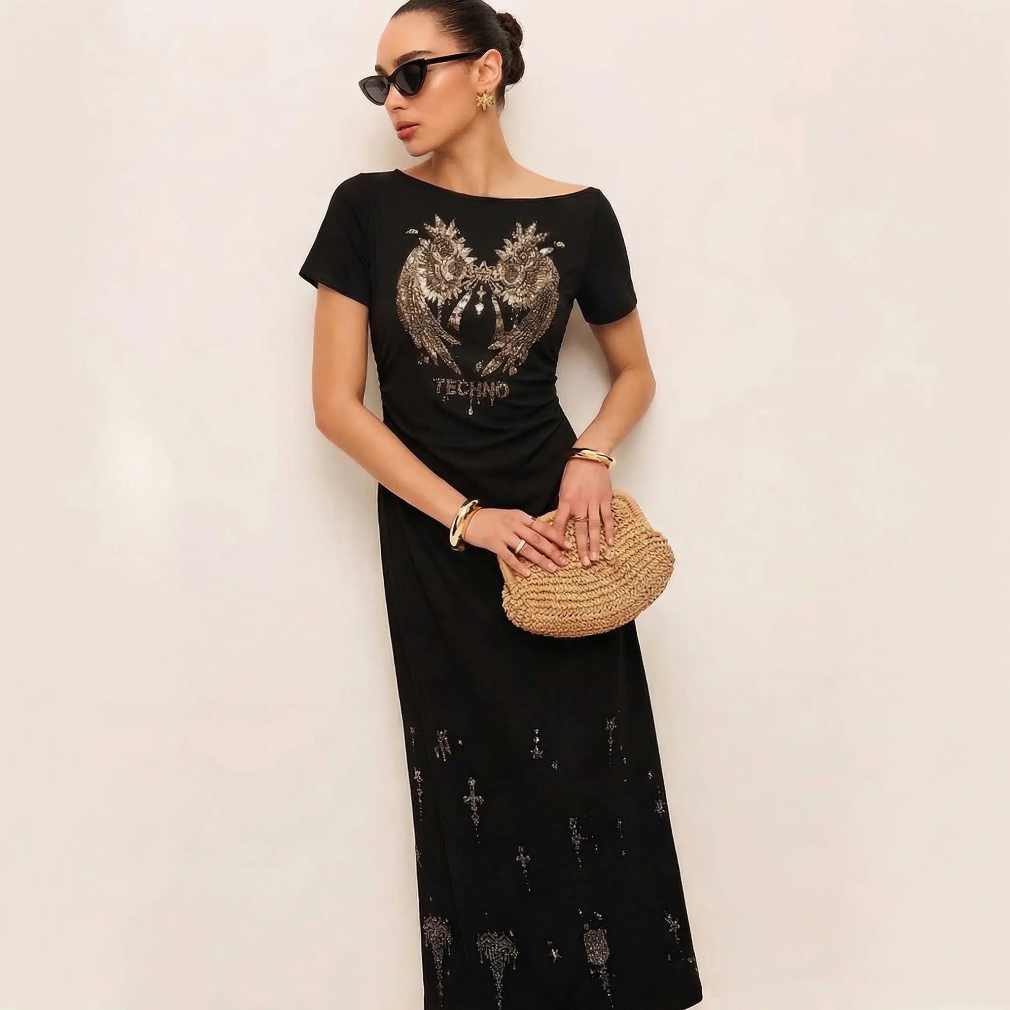 Woman wearing a black dress with a pattern, holding a small bag against a plain background, TCH Rhinestone Angel Wing Black Dress