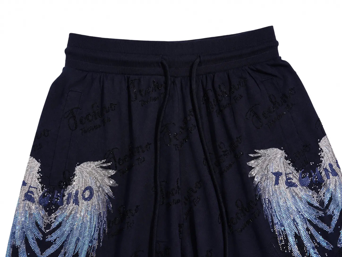 Close-up of dark navy pleated fabric with a drawstring waistband, repeated tonal script text, and large silver-blue wing motifs near the lower sides. TCH Rhinestone Angel Wing Gradient Cargo Shorts