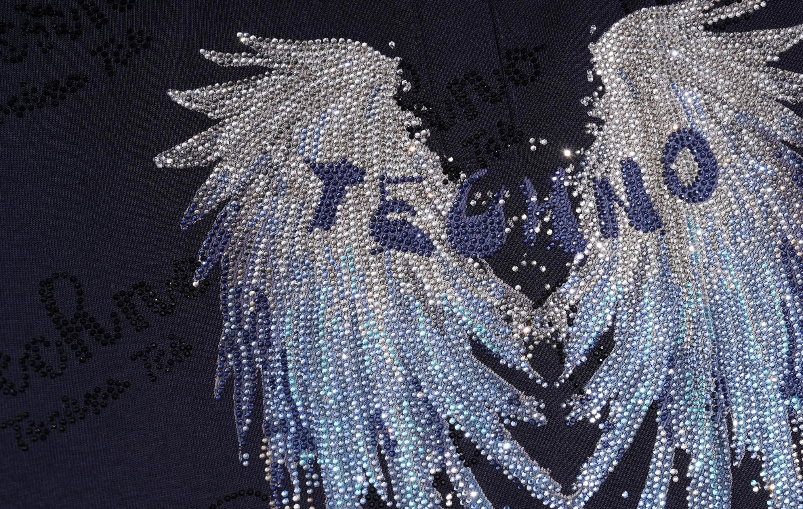 A close-up of a dark navy or black garment featuring a large rhinestone-embellished angel wing design with the word 'TECHNO' across the center. TCH Rhinestone Angel Wing Gradient Cargo Shorts