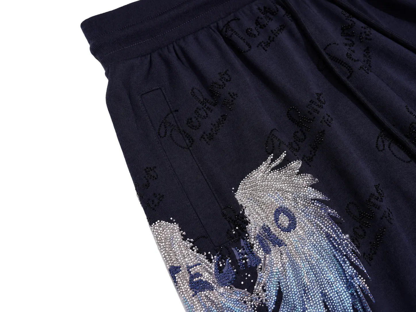 Close-up of navy blue shorts featuring an embroidered wave design embellished with rhinestones in silver, blue, and white, alongside black script embroidery. TCH Rhinestone Angel Wing Gradient Cargo Shorts