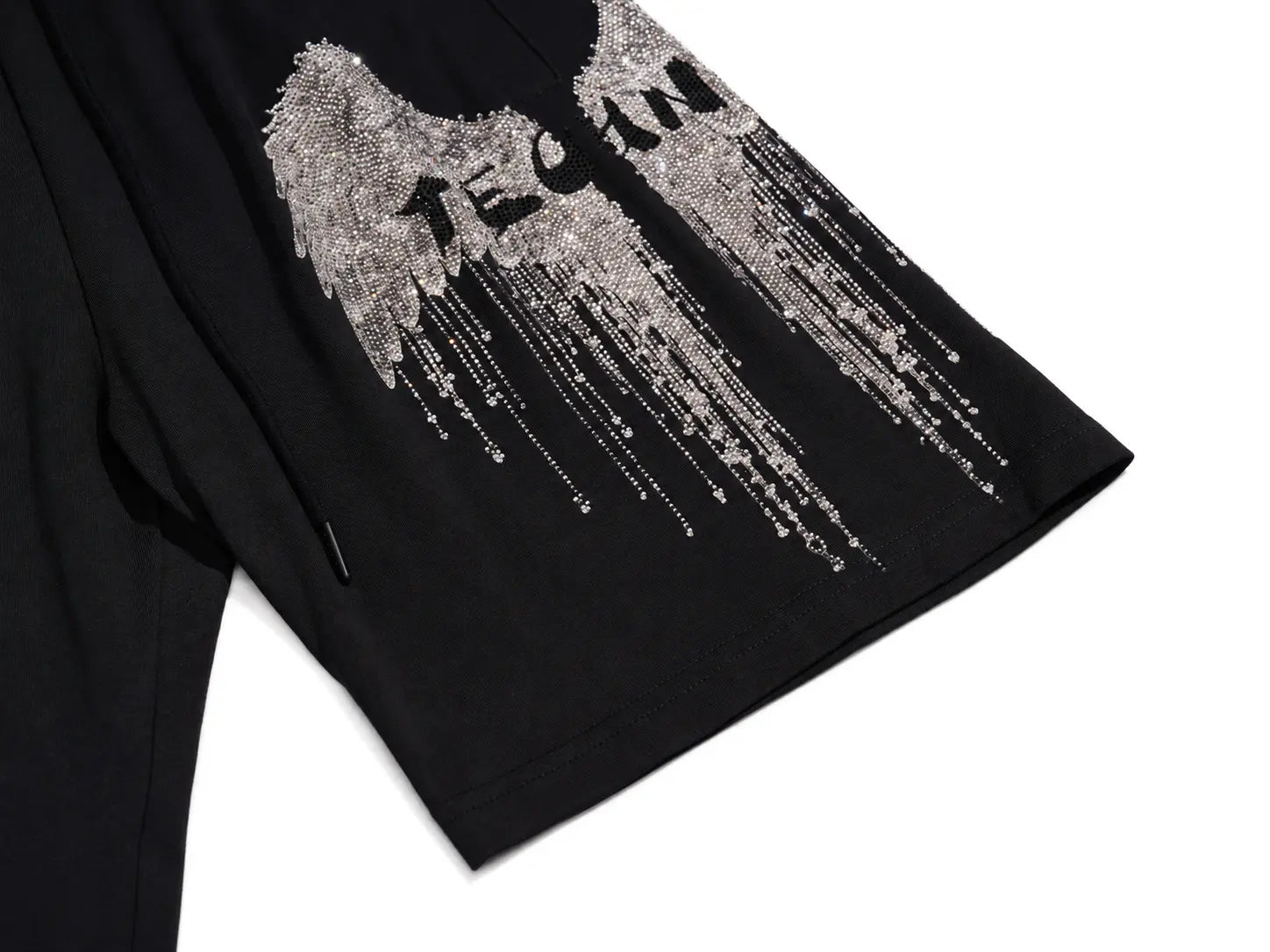 Close-up of a black garment featuring a large silver wing graphic with the word 'TEEN' integrated into the design, on a white background. TCH Rhinestone Angel Wing Graphic Shorts
