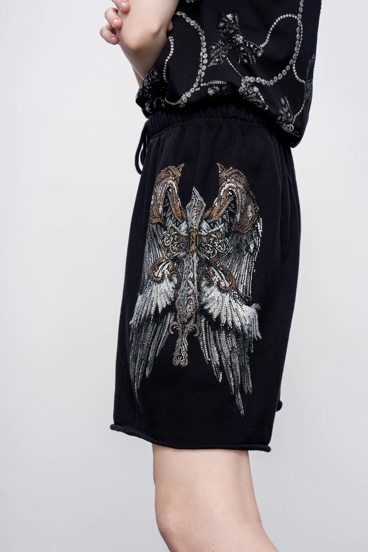 TCH Rhinestone Angel Wings Black Sweat Shorts TCH angel wings shorts Rhinestone black sweat shorts Black graphic shorts Angel wing sweat shorts Embellished black shorts Rhinestone streetwear shorts Y2K black shorts Relaxed fit sweat shorts Gothic graphic shorts Black casual drawstring shorts