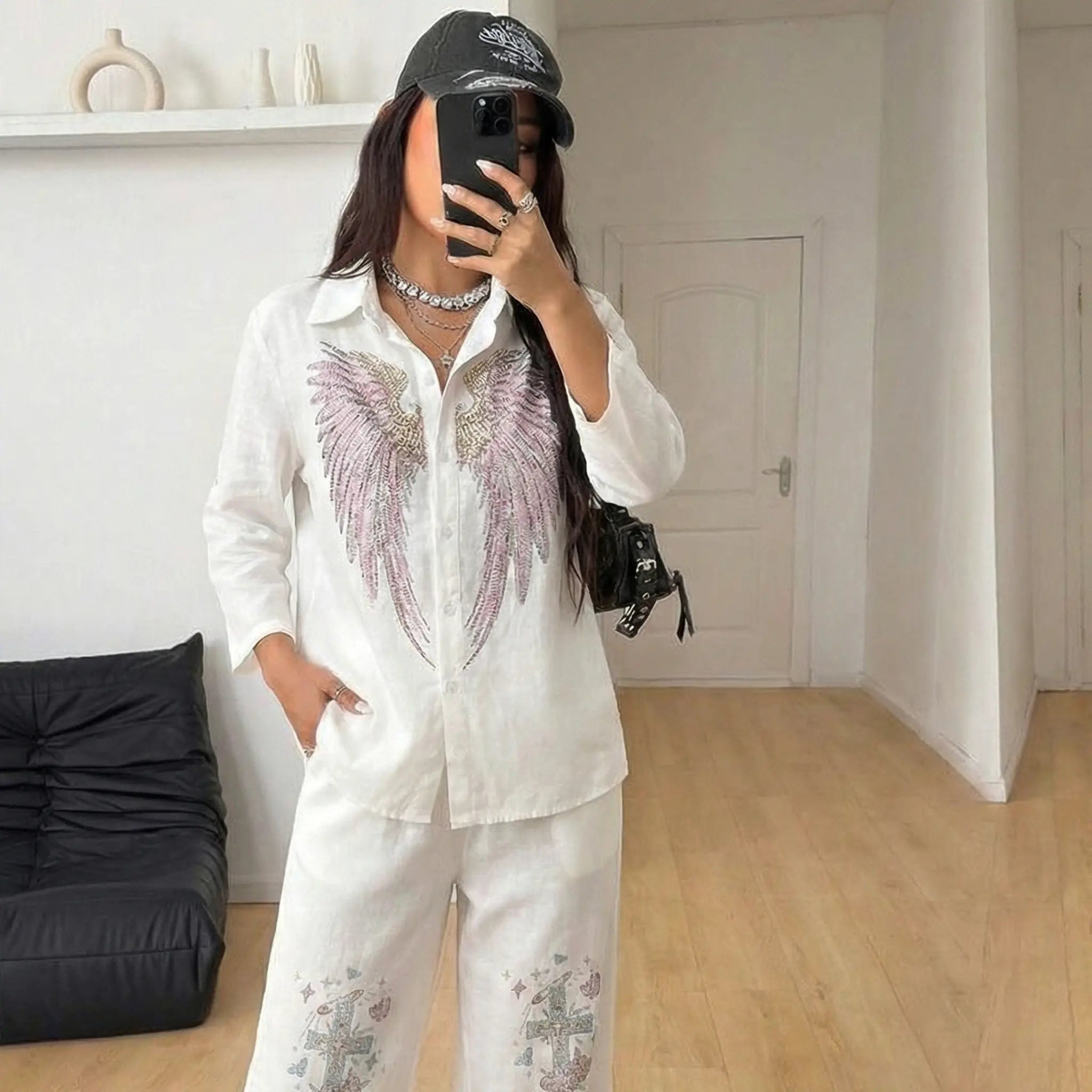 Person wearing a white outfit with decorative elements in a room. TCH Rhinestone Angel Wings & Cross Set