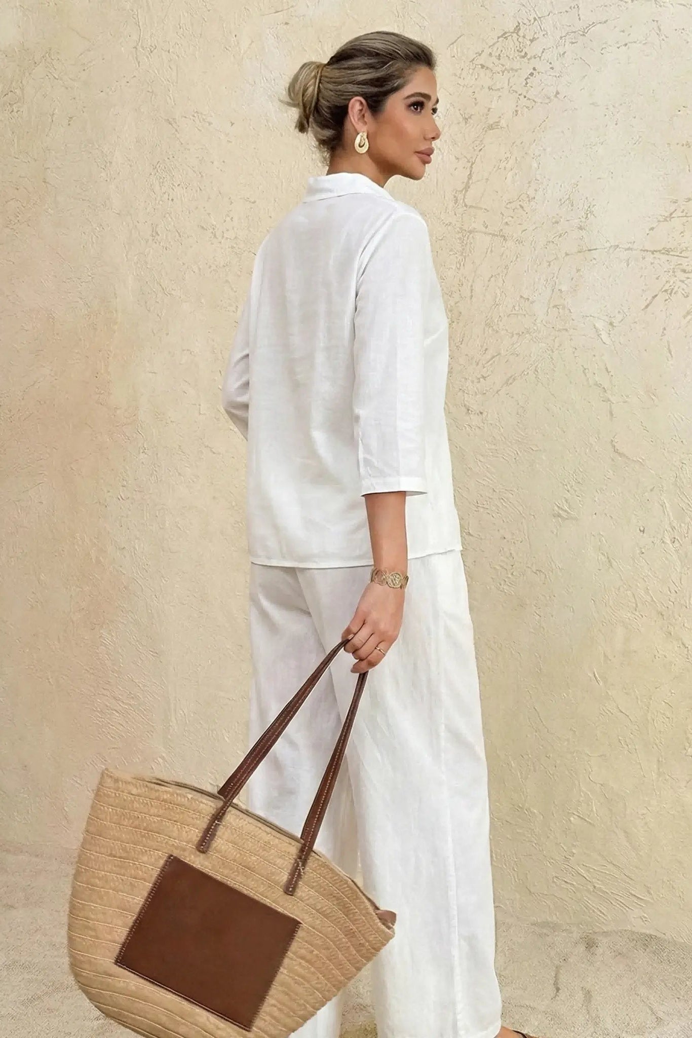 Woman in white outfit holding a straw bag against a beige wall, TCH Rhinestone Angel Wings & Cross Set