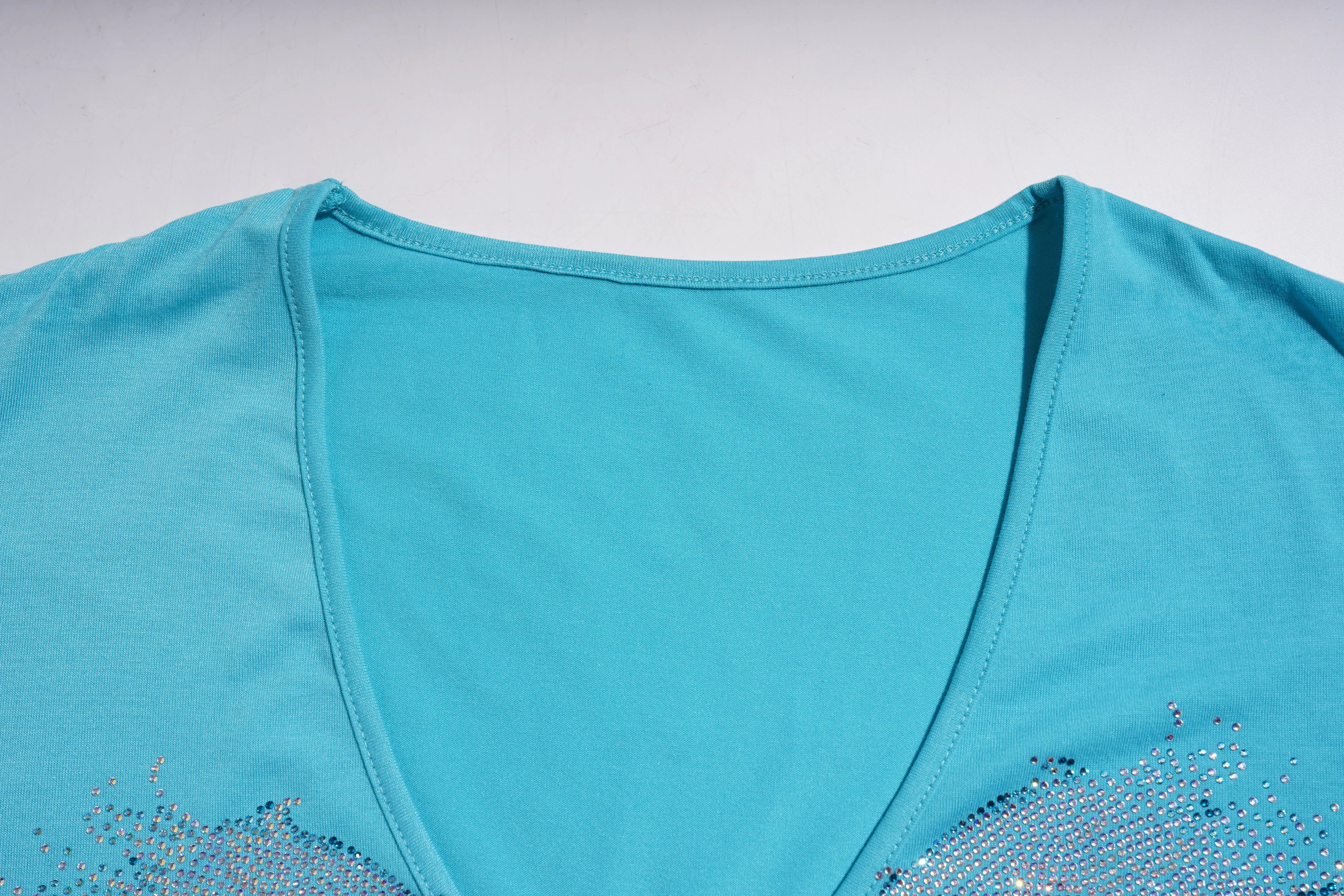 Close-up of a turquoise top with decorative elements on a light gray background, TCH Rhinestone Angel Wings V-Neck T-Shirt