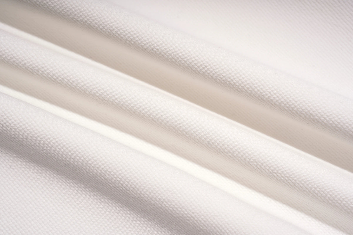 A close-up of draped white fabric with soft diagonal folds and a fine woven texture. TCH Rhinestone Angel Wings White Straight-Leg Jeans