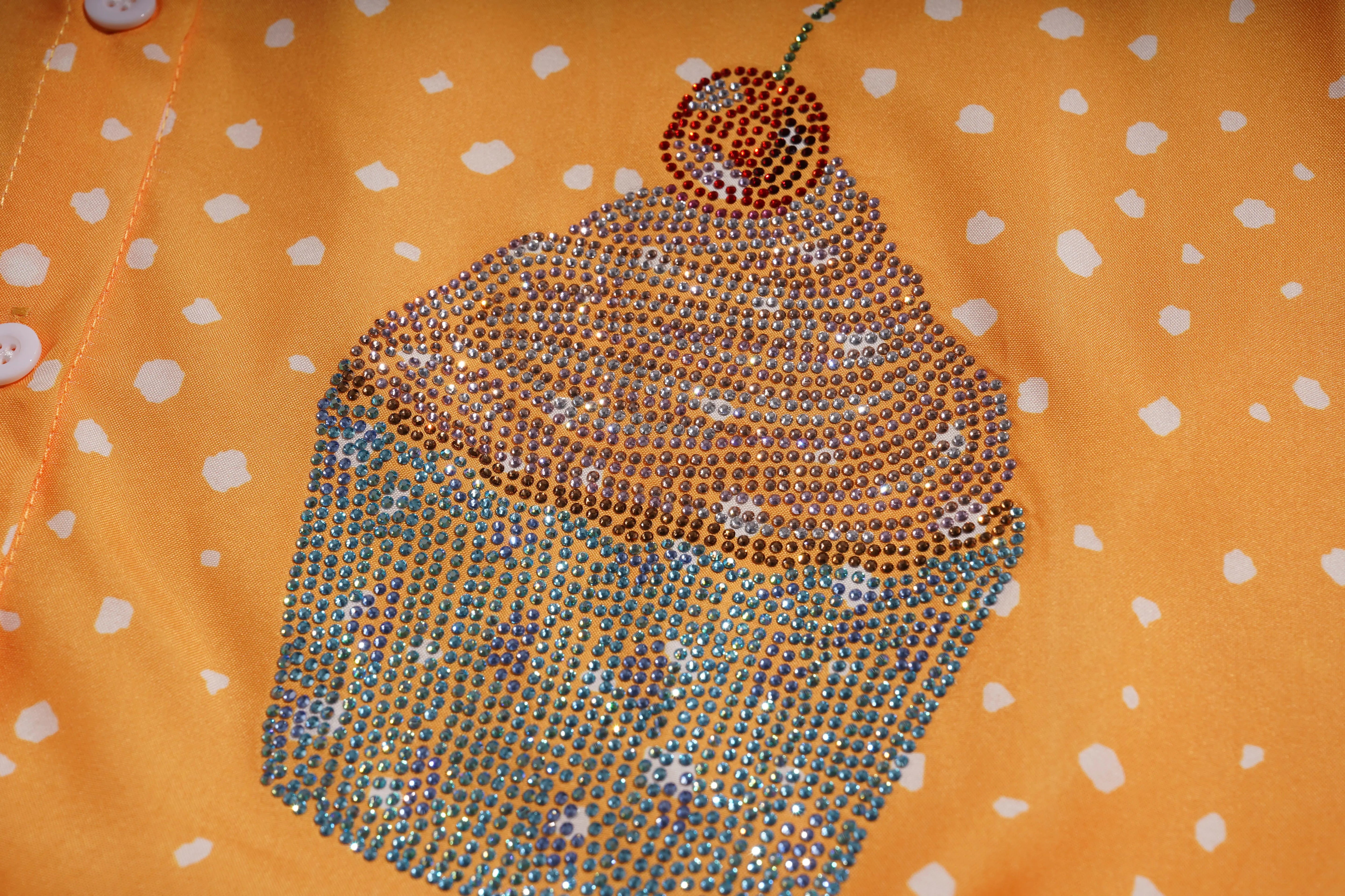 Decorative cupcake design on a fabric with orange background and white polka dots, TCH Rhinestone Animal Polka Dot Shirt