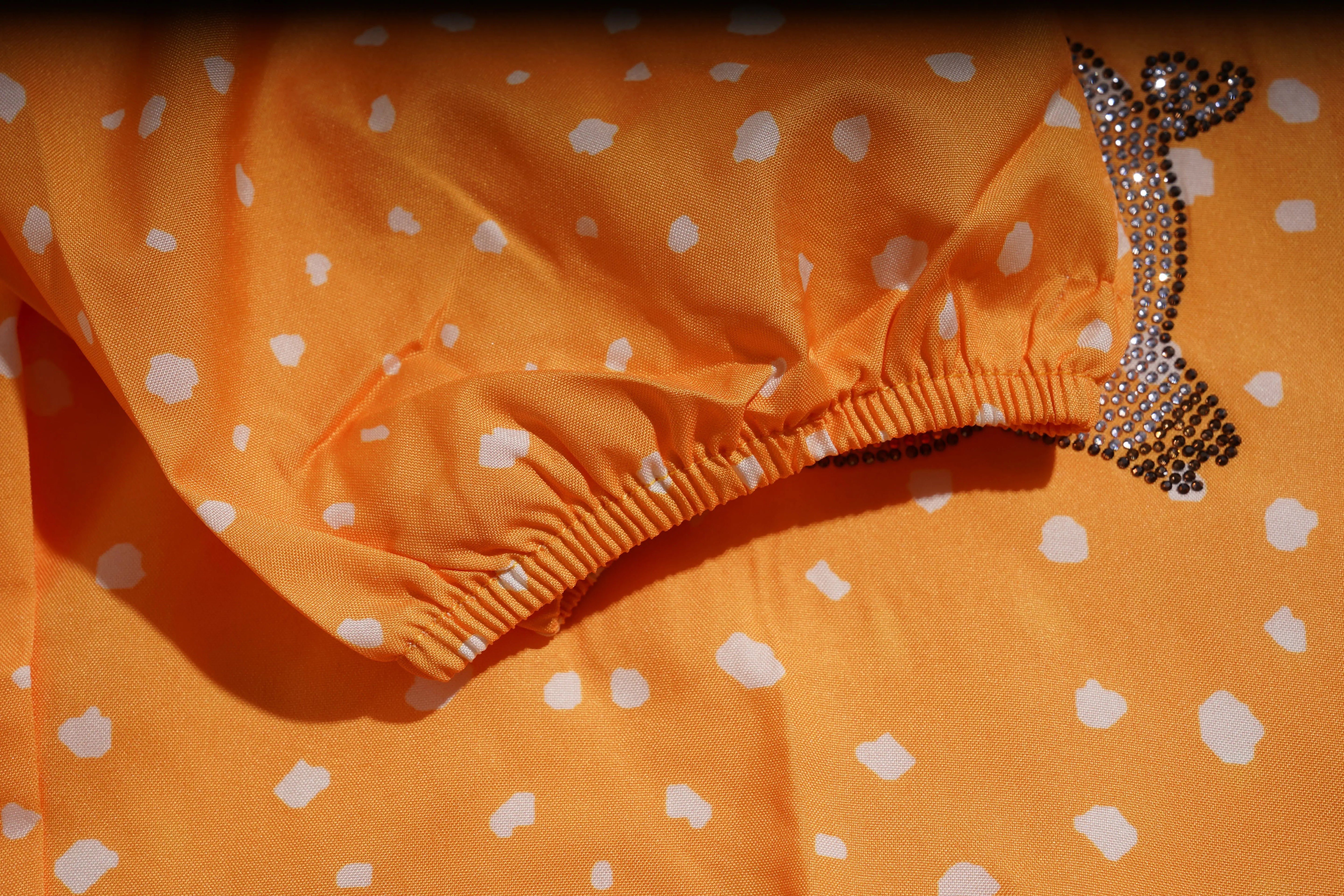 Orange polka dot garment with a decorative brooch on an orange background, TCH Rhinestone Animal Polka Dot Shirt