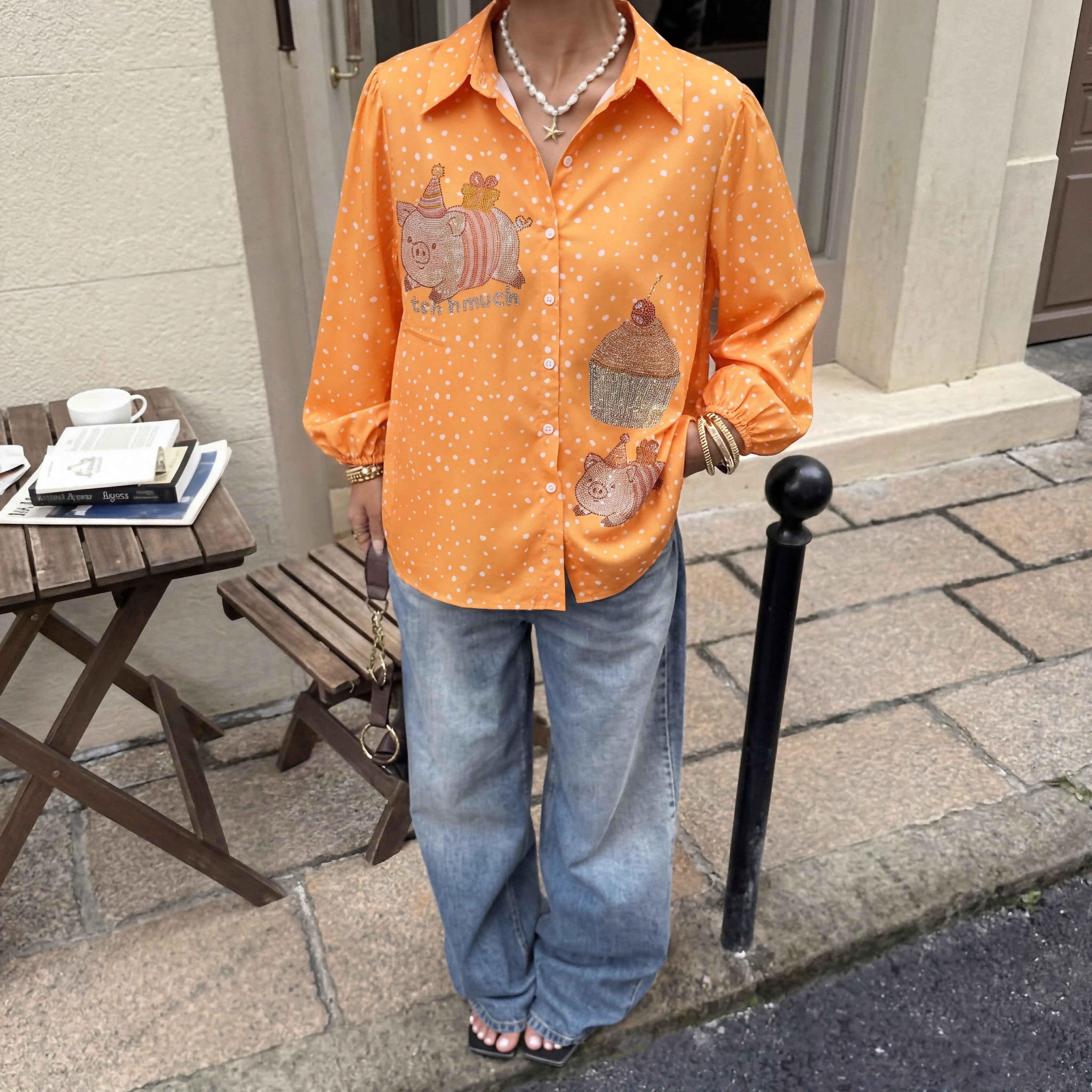 Person wearing an orange patterned shirt and blue jeans standing on a sidewalk. TCH Rhinestone Animal Polka Dot Shirt