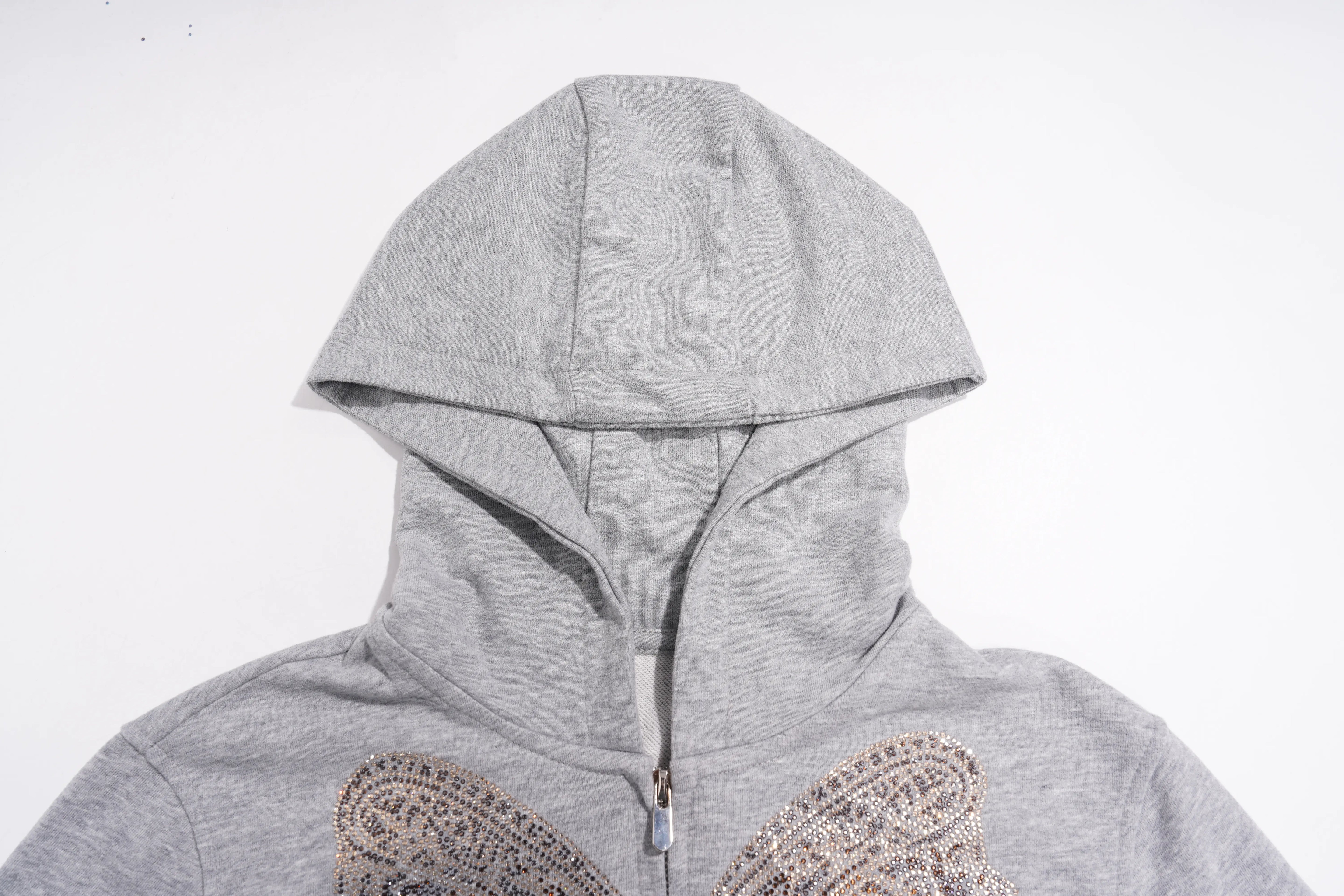 A close-up of a light gray heathered zip-up hoodie with a hood and a decorative paisley embellishment on the chest, shown against a plain white background. TCH Rhinestone Bow 3-Piece Lounge Set