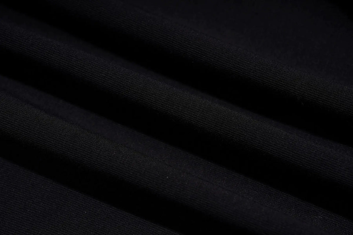 A close-up of dark black ribbed fabric with soft diagonal folds and texture. TCH Rhinestone Bow Cherry Drawstring Long Sleeve Top