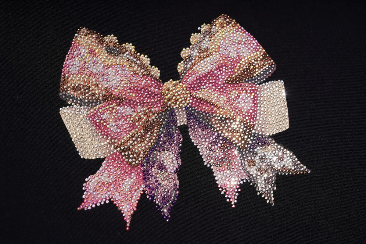 A large, elaborate hair bow embellished with pink, purple, and gold rhinestones, set against a solid black background. TCH Rhinestone Bow Cherry Drawstring Long Sleeve Top