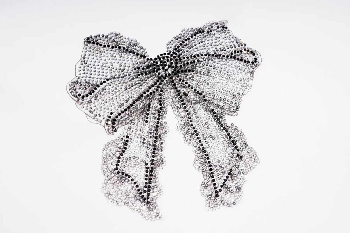 A large, elaborate bow embellished with intricate rhinestone and beadwork, photographed against a seamless white background. TCH Rhinestone Bow Graphic Fitted Long Sleeve Top