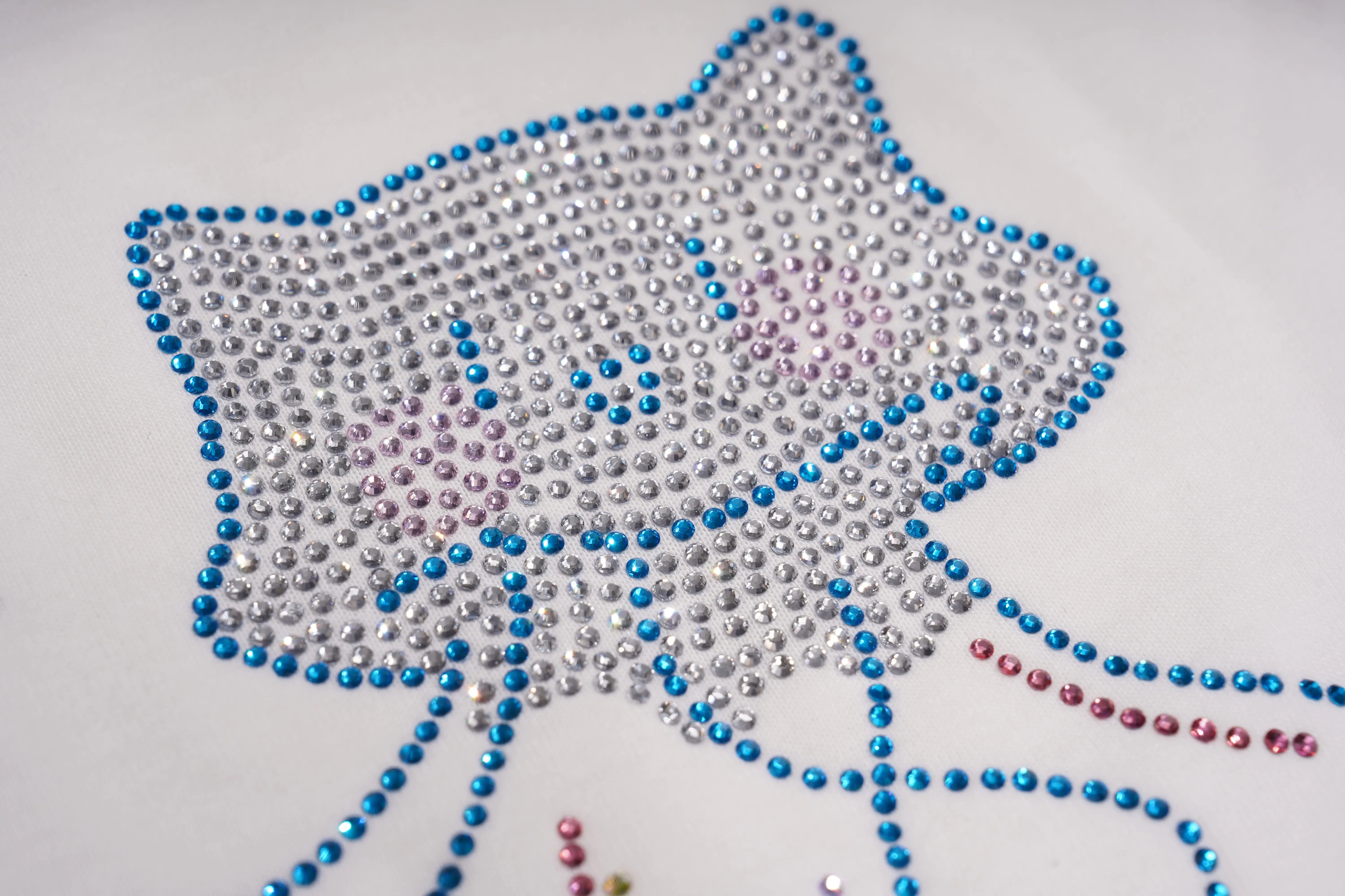 A close-up of a rhinestone design forming a cat face and bow, made with silver, blue, and pink clear rhinestones on a white background. TCH Rhinestone Bow Graphic Oversized T-Shirt Dress