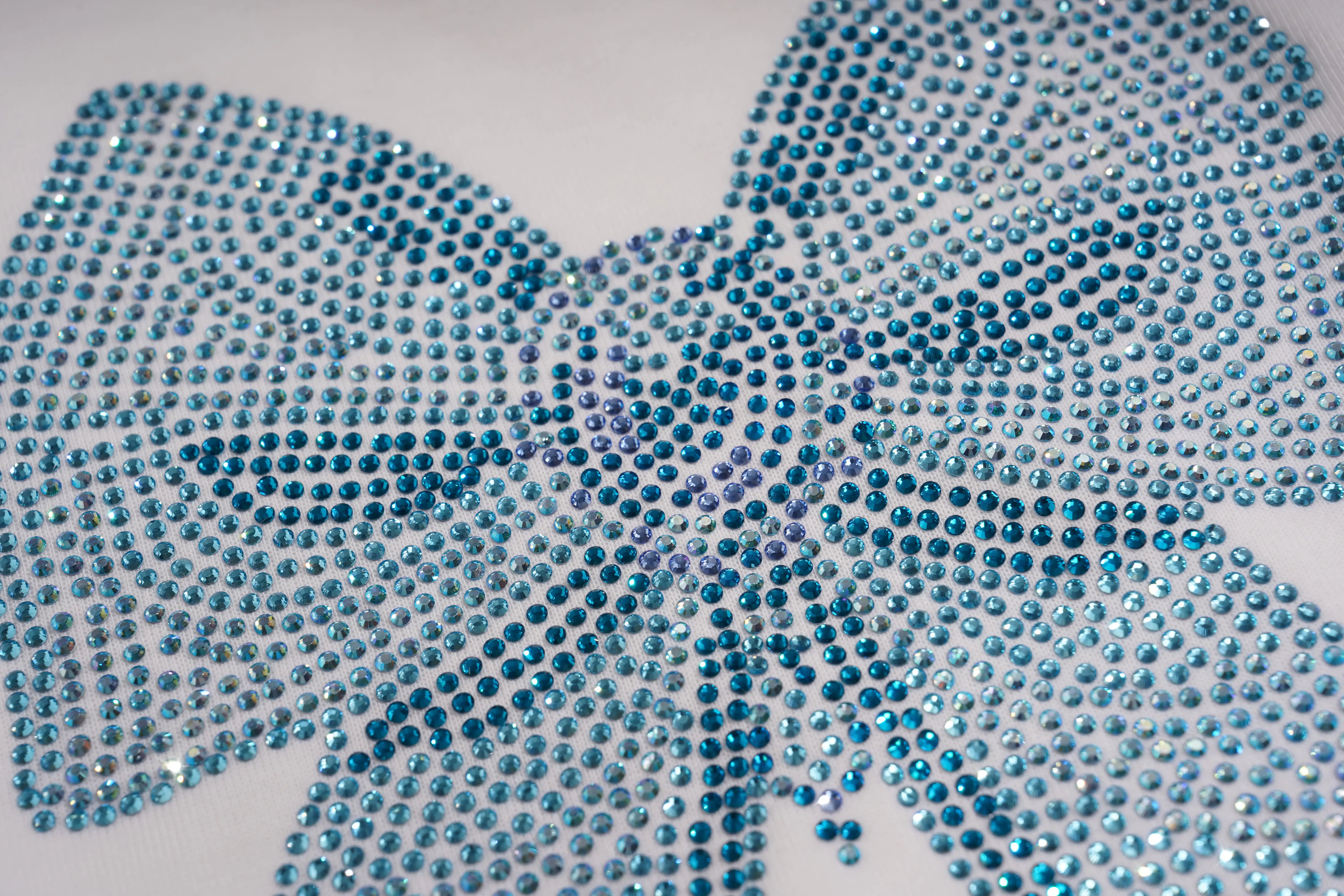 A close-up of a large bow-shaped embellishment covered in sparkling blue rhinestones on a plain white background. TCH Rhinestone Bow Graphic Oversized T-Shirt Dress