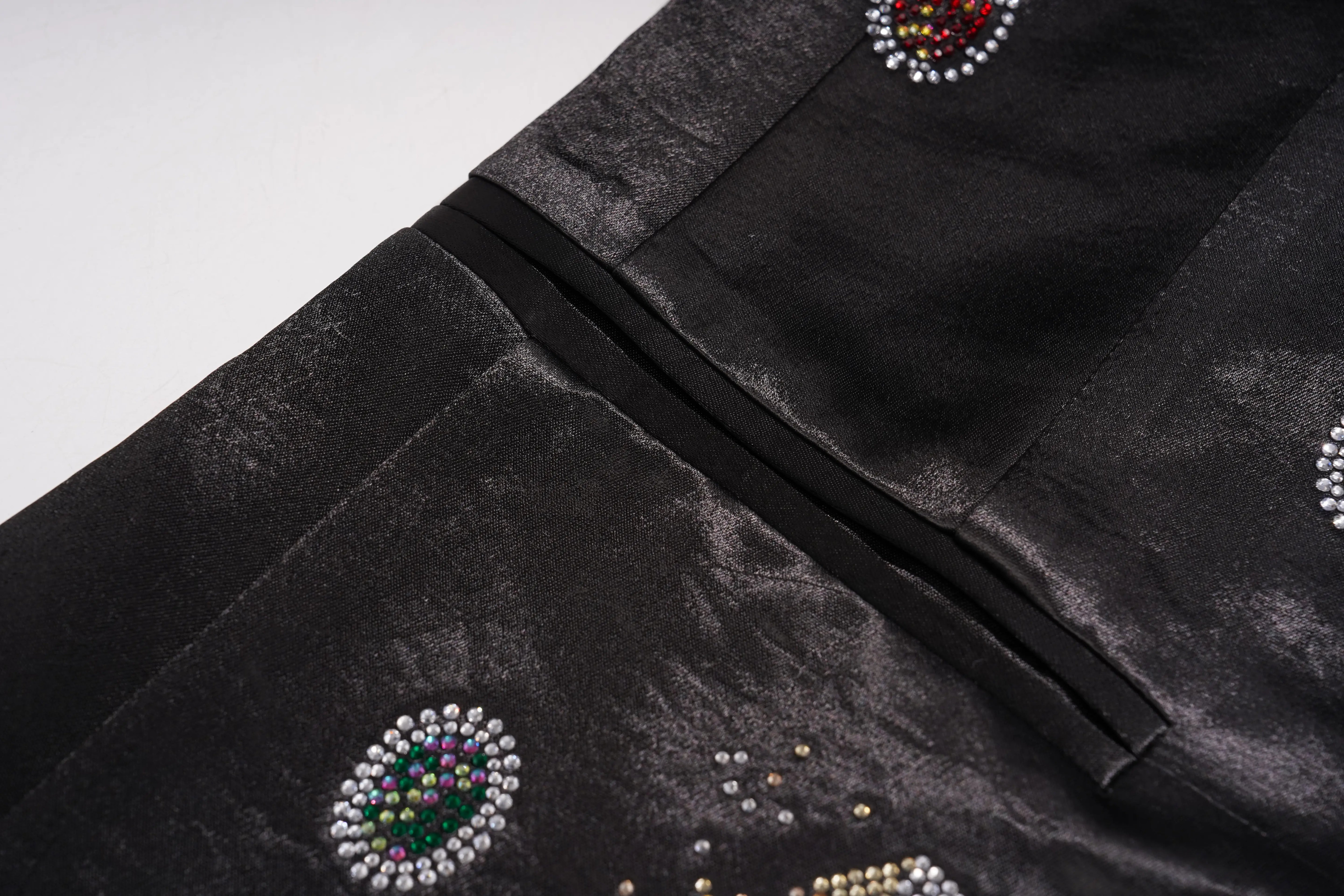 Close-up of a black velvet garment with embroidered circular beadwork and a black satin trim detail, shown against a light gray background. TCH Rhinestone Bow Satin Blazer