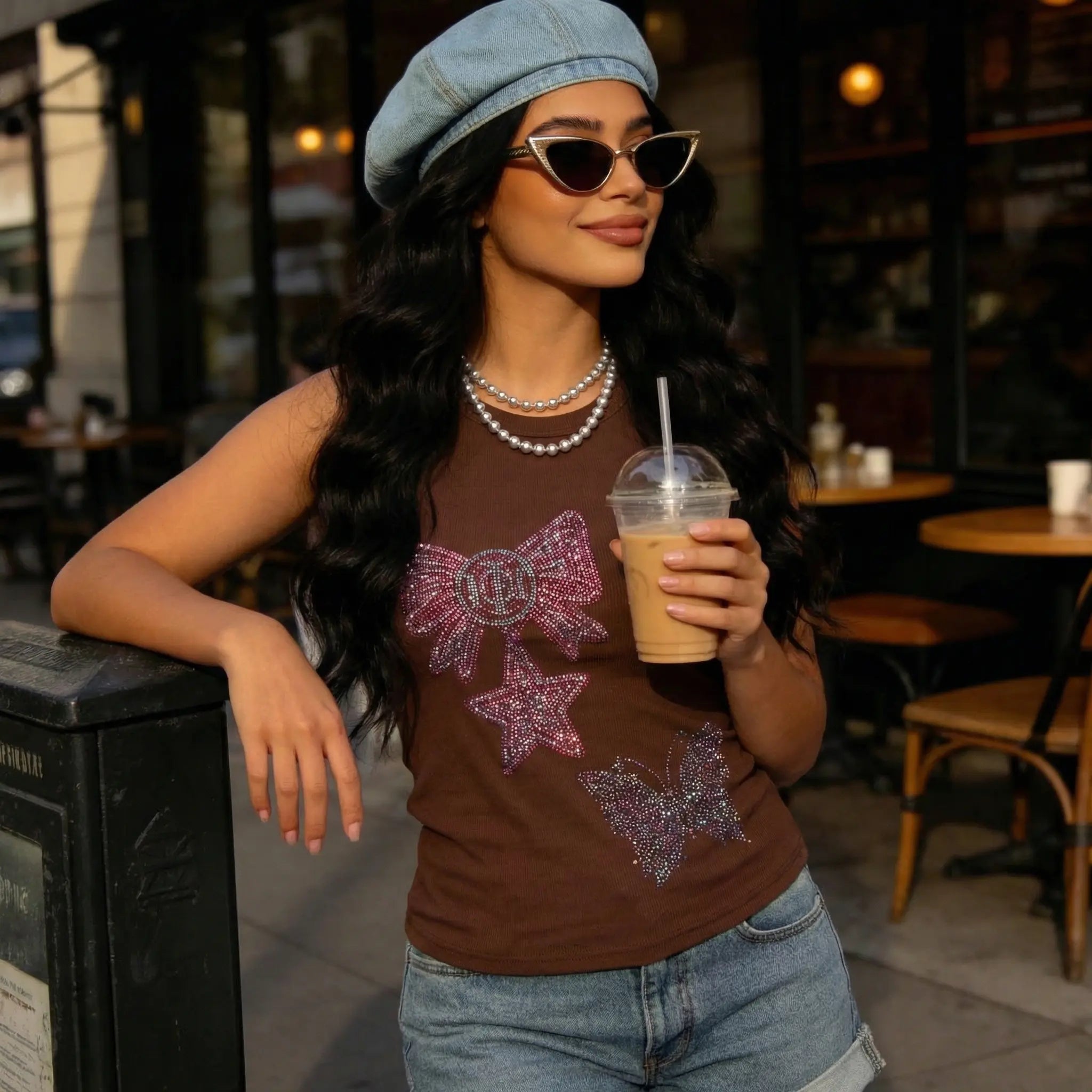 Woman holding a drink in an outdoor cafe setting, TCH Rhinestone Butterfly Bow Tank Top