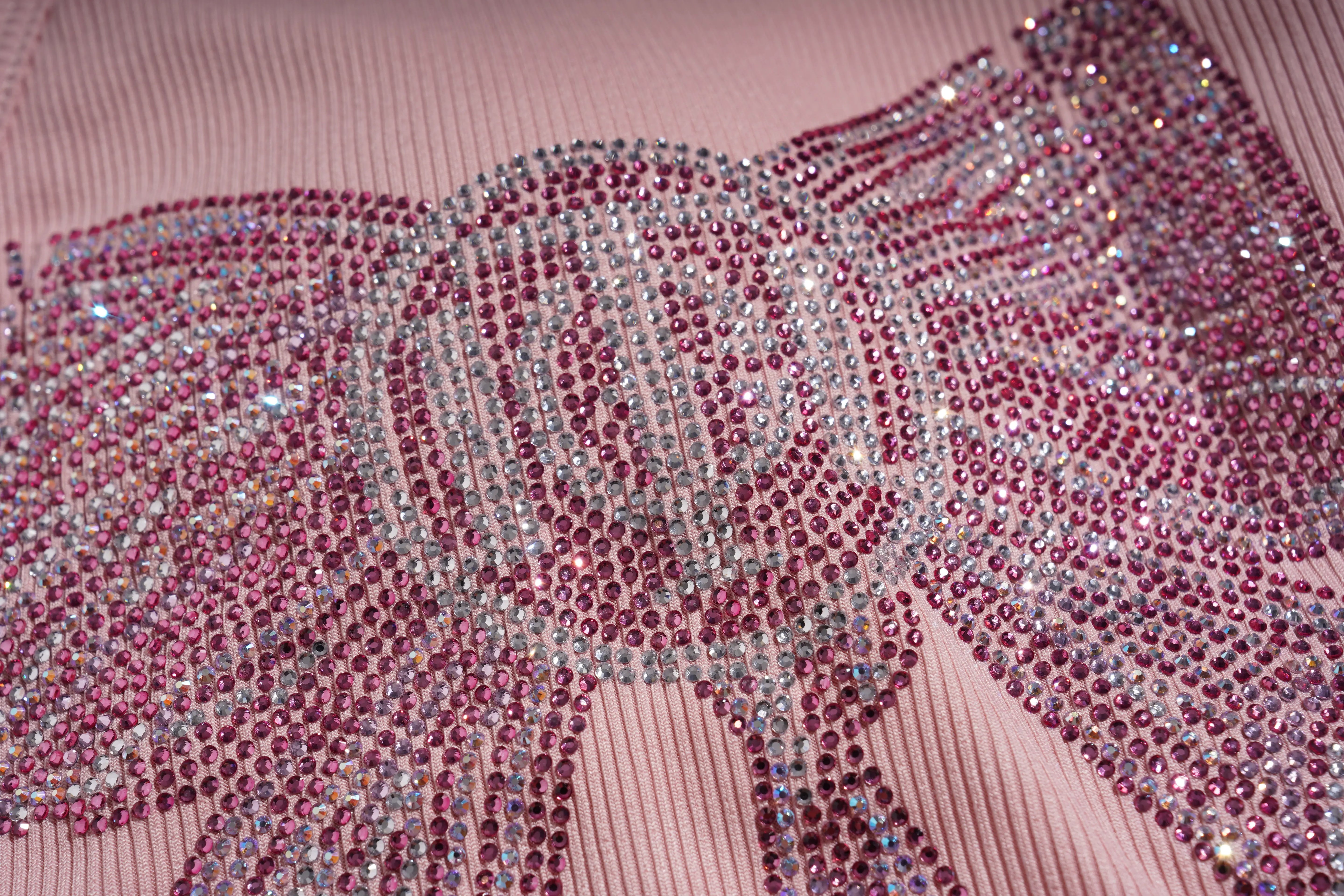 Close-up of a pink fabric with decorative pink and silver embellishments. TCH Rhinestone Butterfly Bow Tank Top