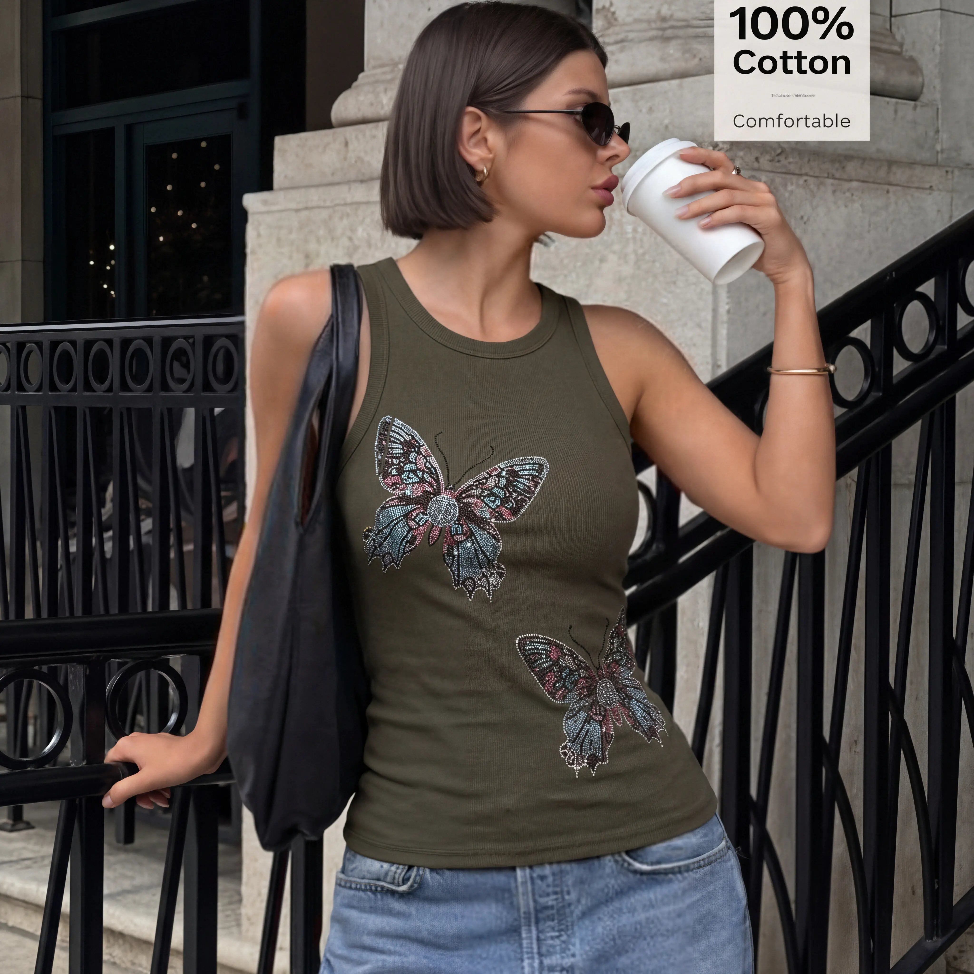 Woman wearing a green tank top with butterfly designs, holding a cup, standing on steps. TCH Rhinestone Butterfly Bow Tank Top
