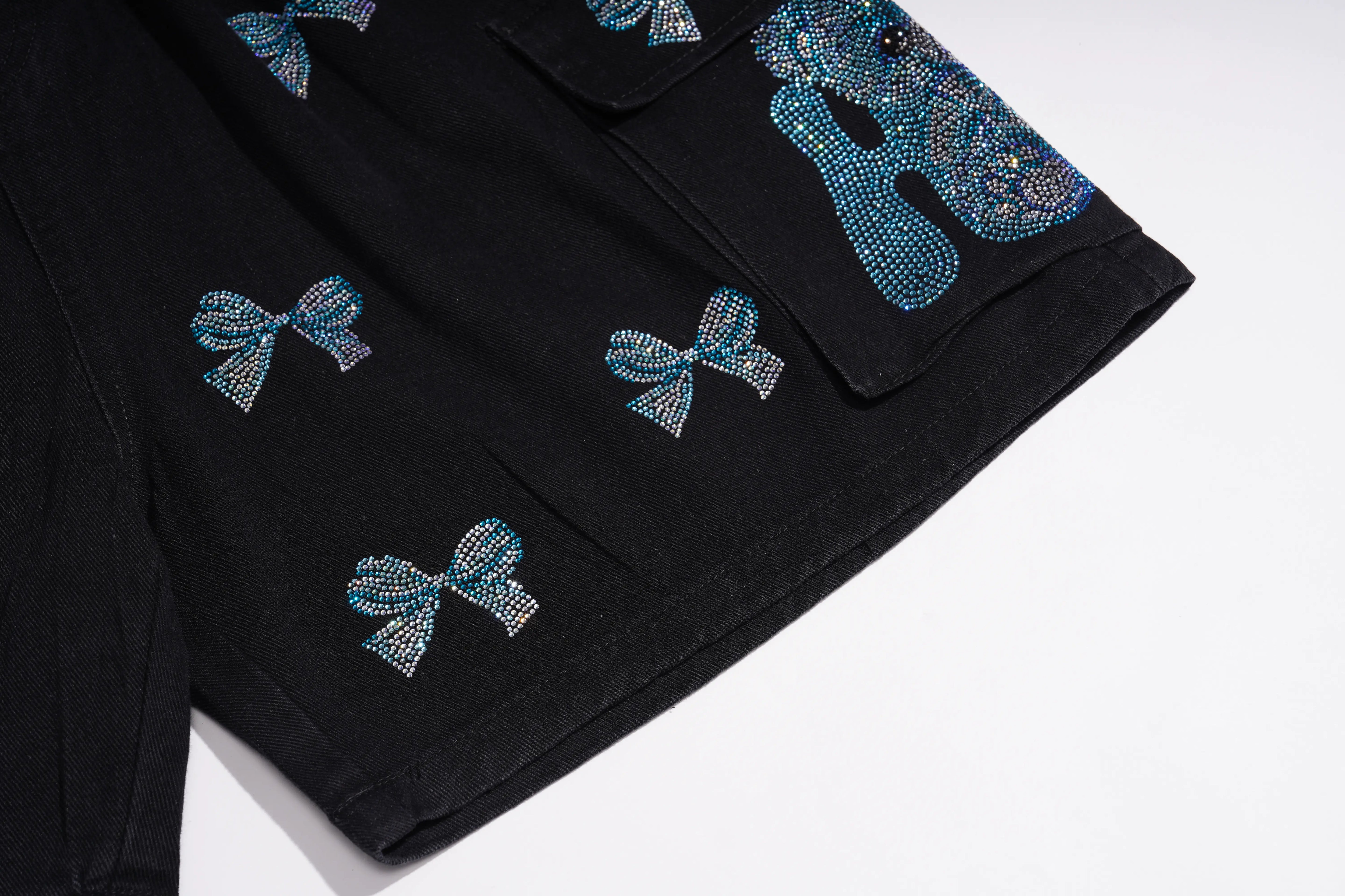 Black denim shorts featuring rhinestone-embellished bow and skull motifs in blue, silver, and black, shown on a clean white background. TCH Rhinestone Butterfly & Dragon Graphic Black Cargo Shorts